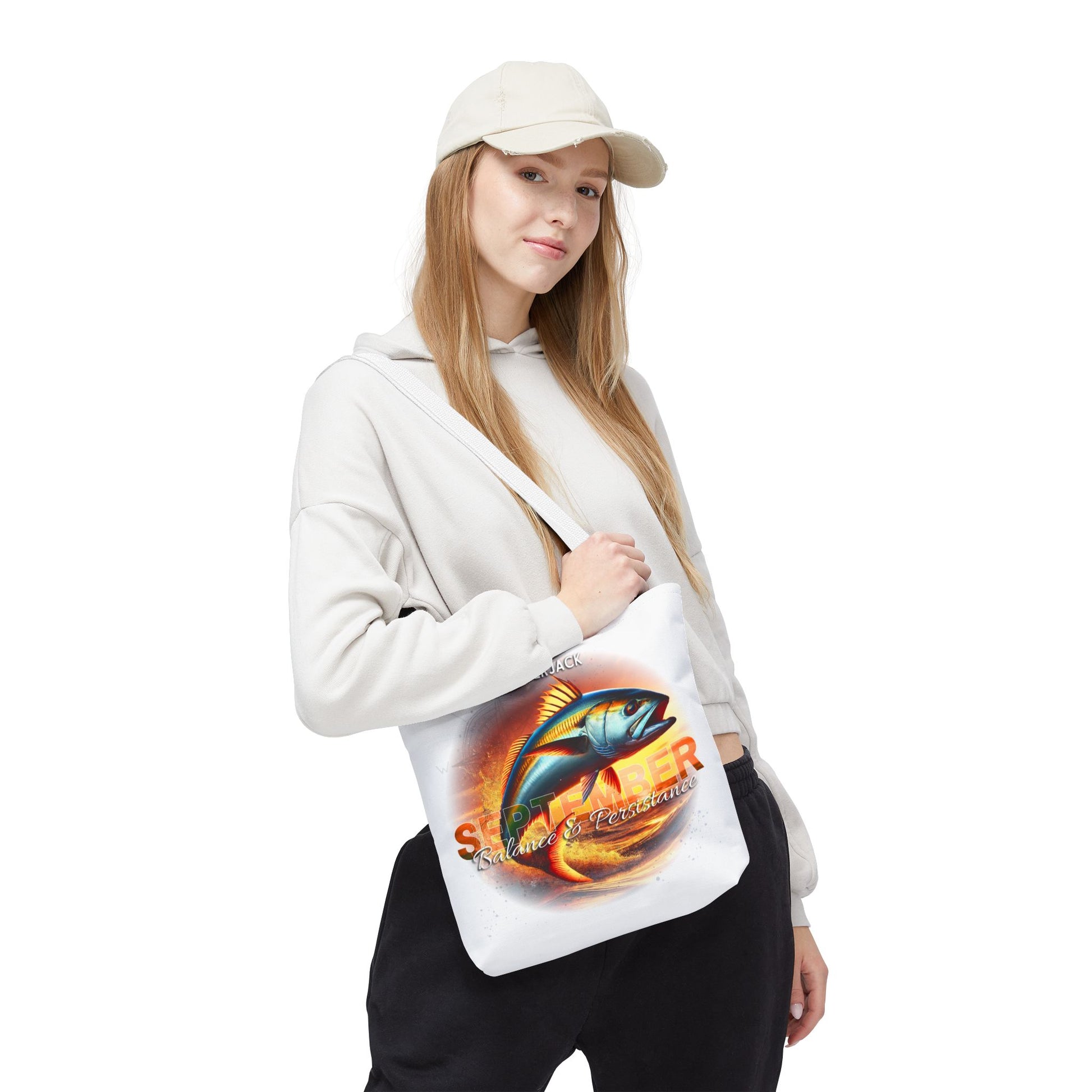 Woman wearing white cap and hoodie holding birth month beach tote with colorful fish design