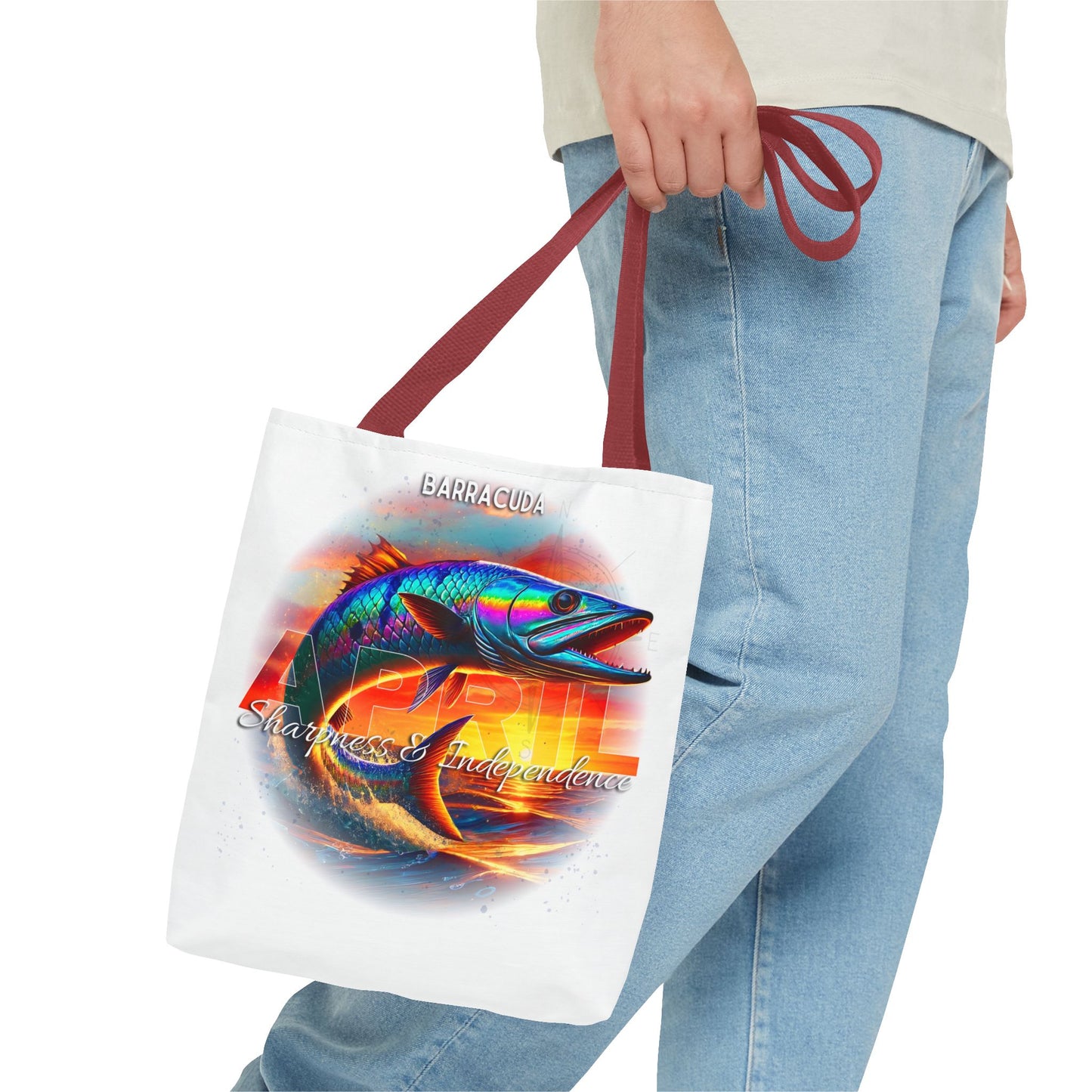 Birth month beach tote with colorful barracuda design and maroon handles held by person wearing jeans