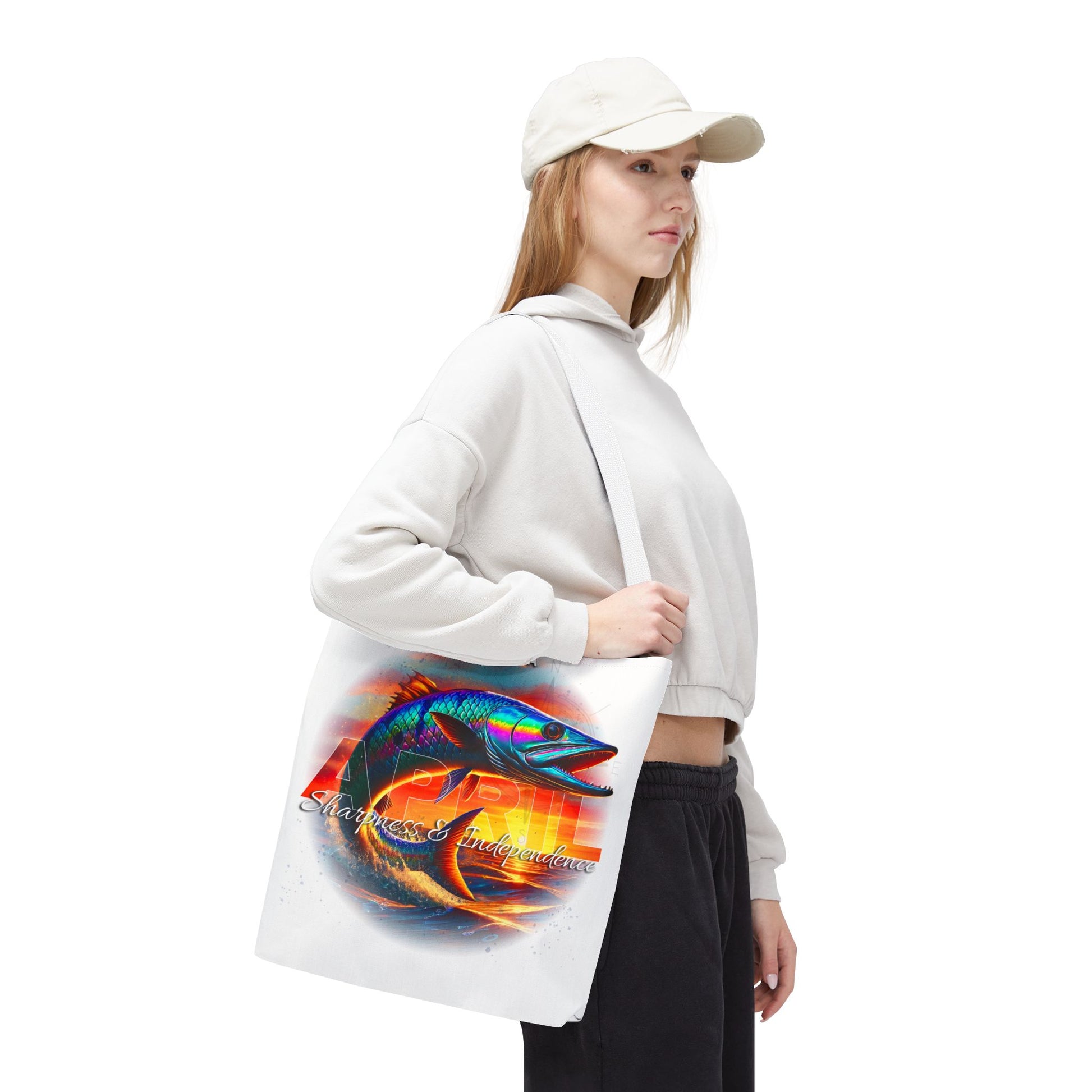 Woman wearing white cap and hoodie holding birth month beach tote with colorful fish design