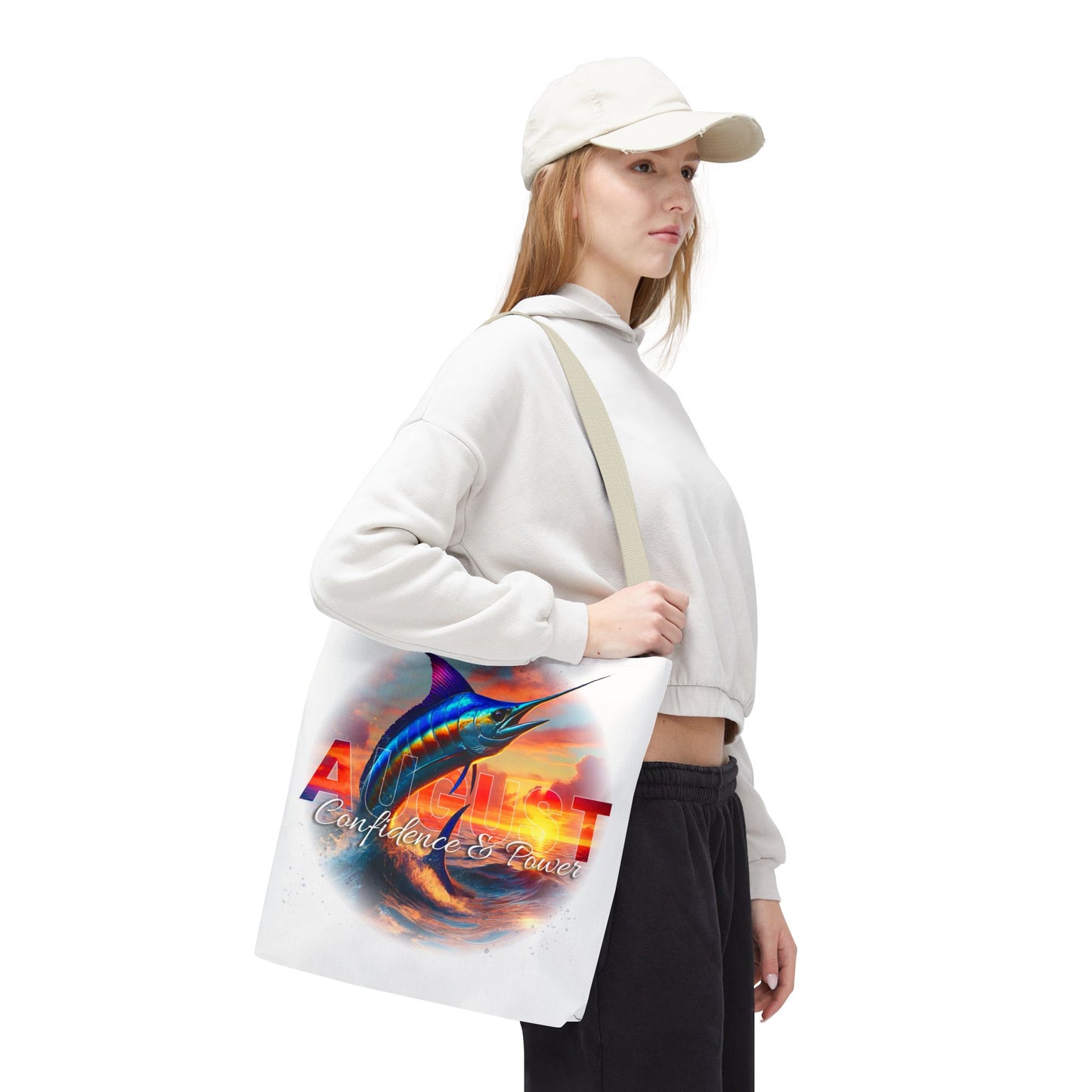 Woman wearing a white cap carrying a birth month beach tote with colorful marlin design and August text