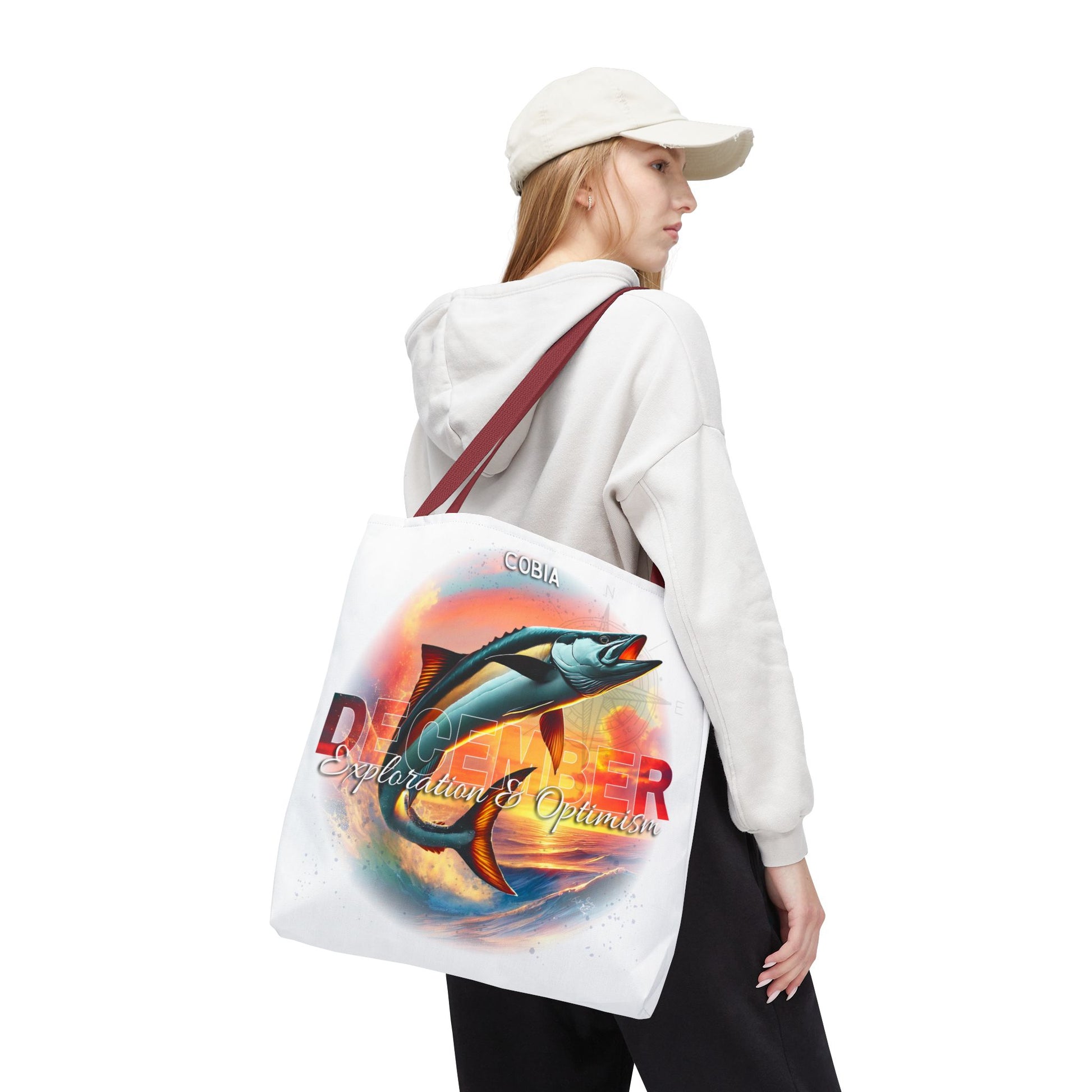 Birth month beach tote featuring colorful fish and ocean design worn by woman in white hoodie and cap