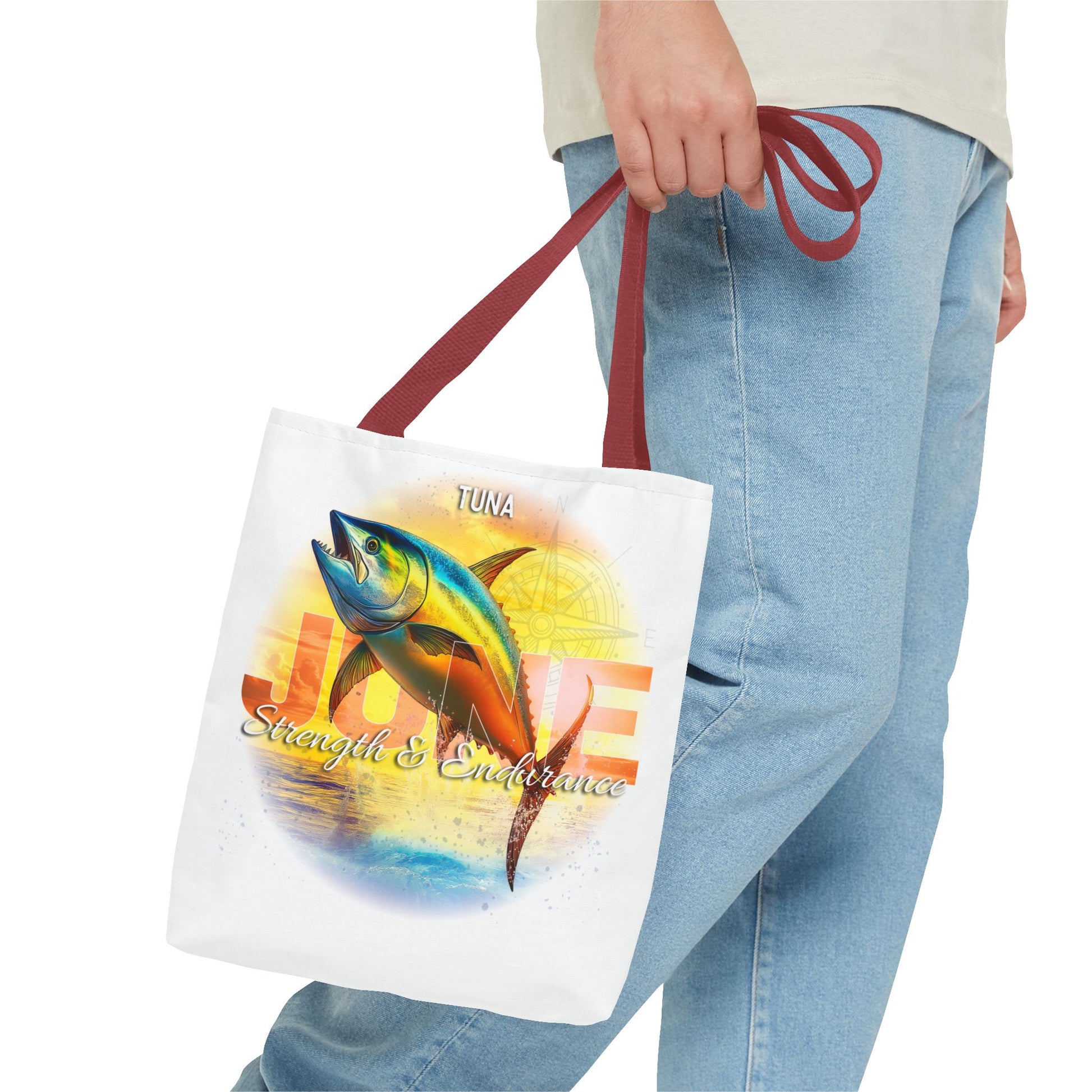 Birth month beach tote with colorful tuna fish design and maroon handles worn by person in jeans