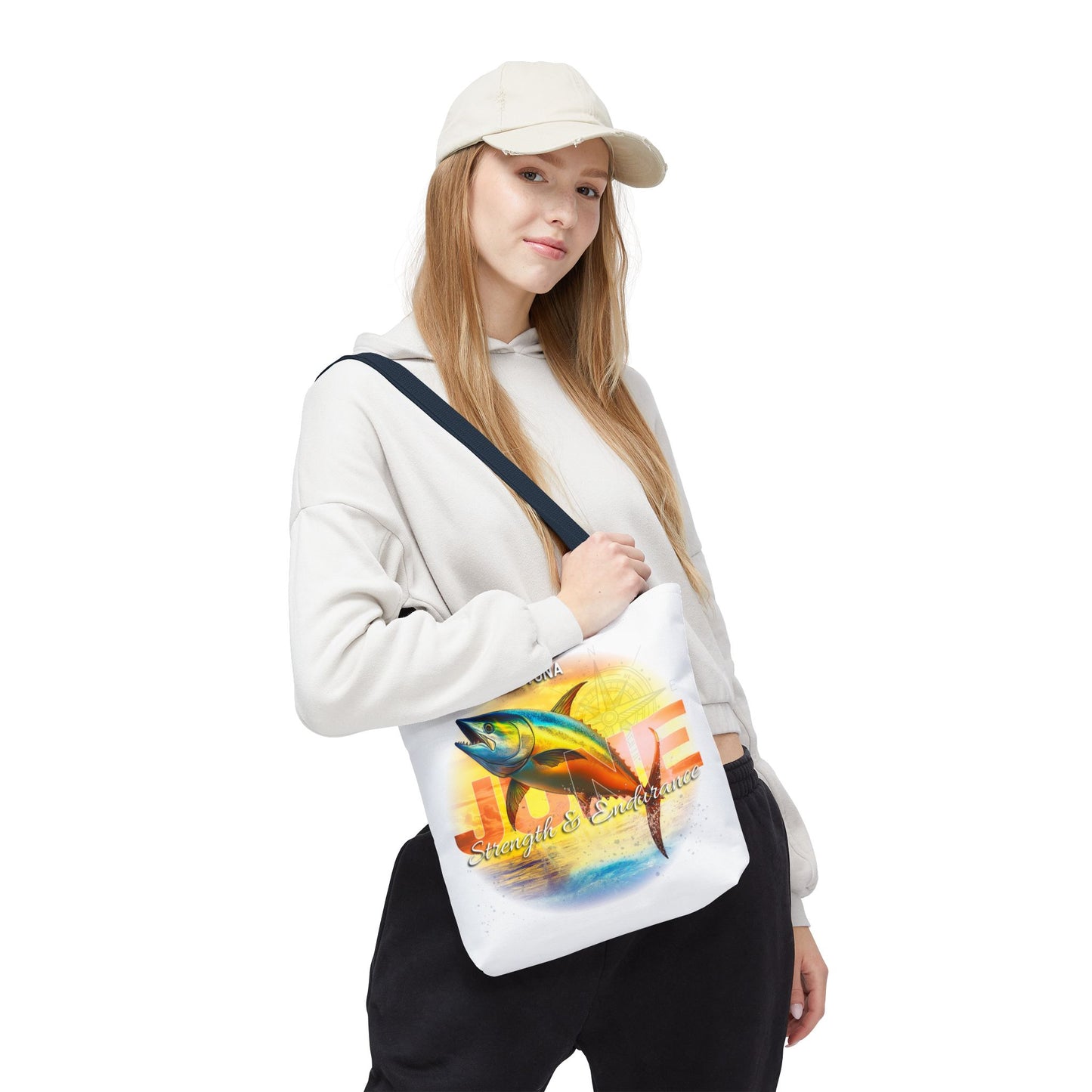 Woman wearing a white cap and hoodie carrying a birth month beach tote with colorful fish and sunset design