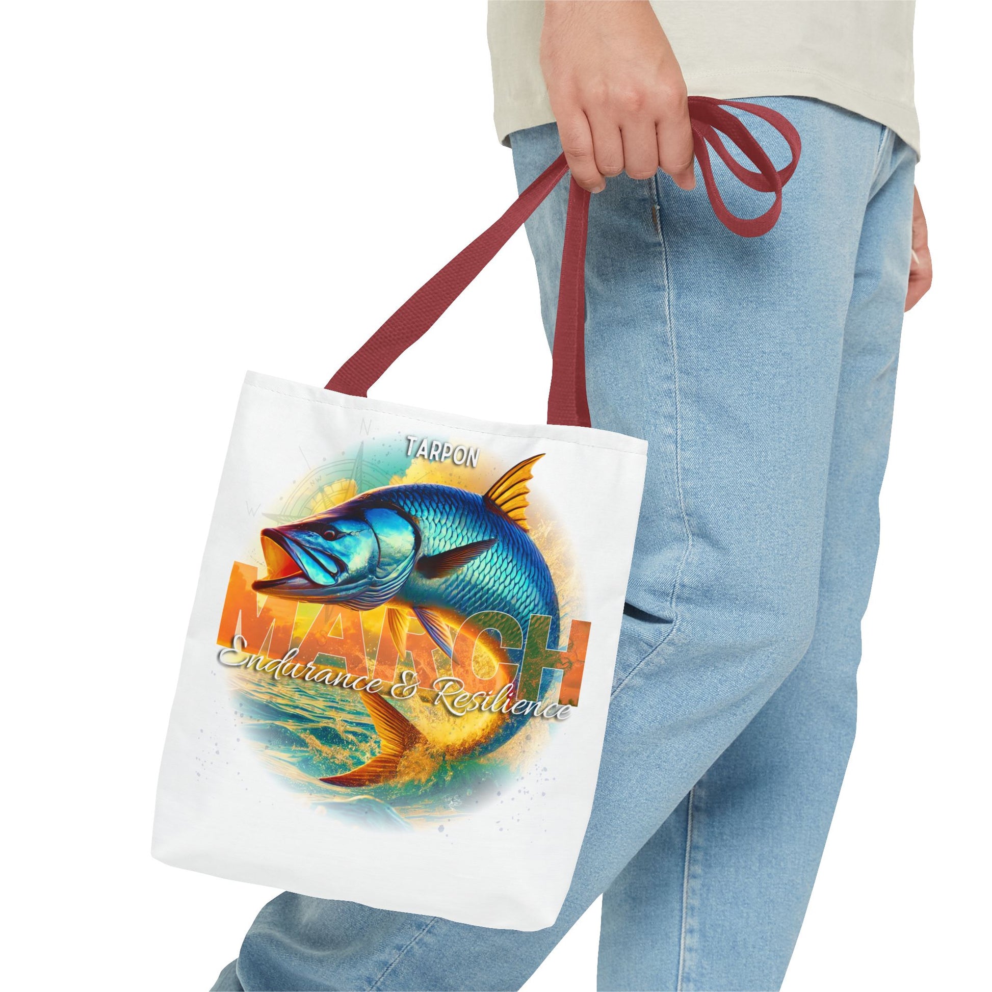 Birth month beach tote with blue tarpon fish design and red handles carried by person