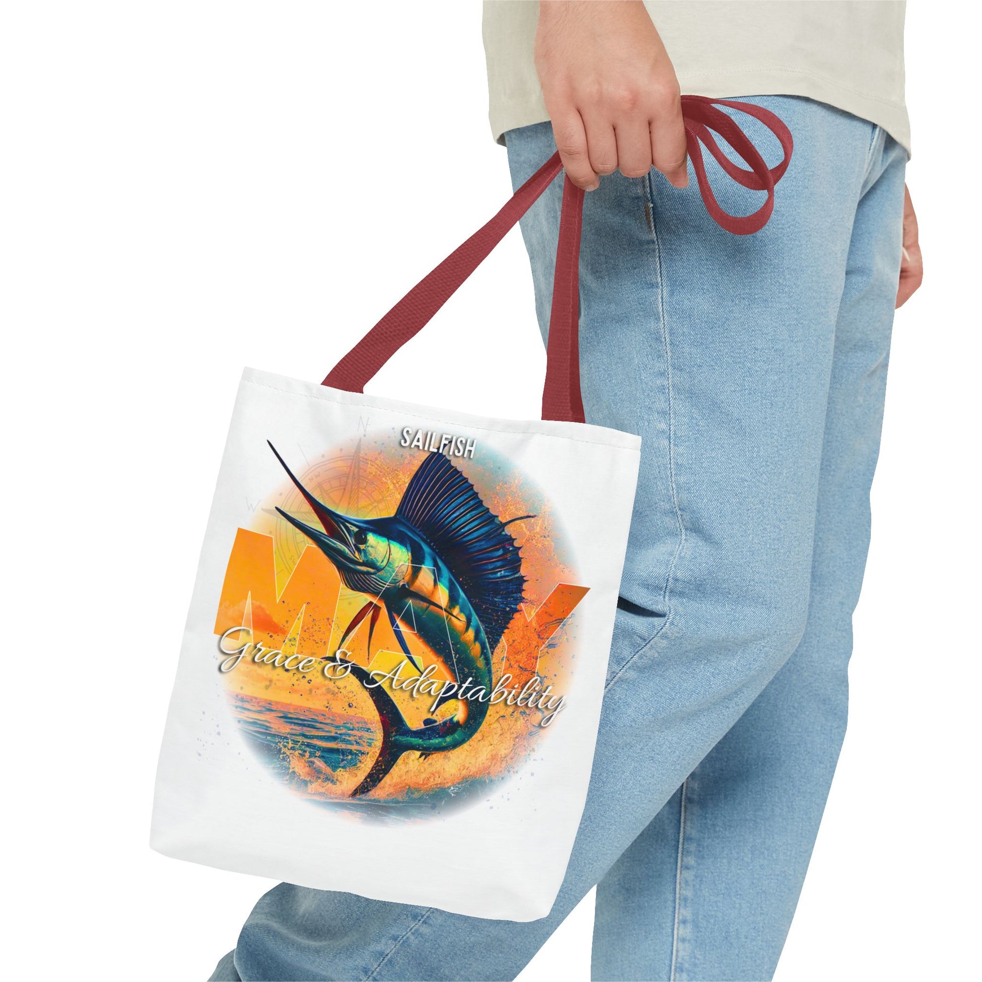 Birth month beach tote with sailfish design and maroon handles held by person in jeans
