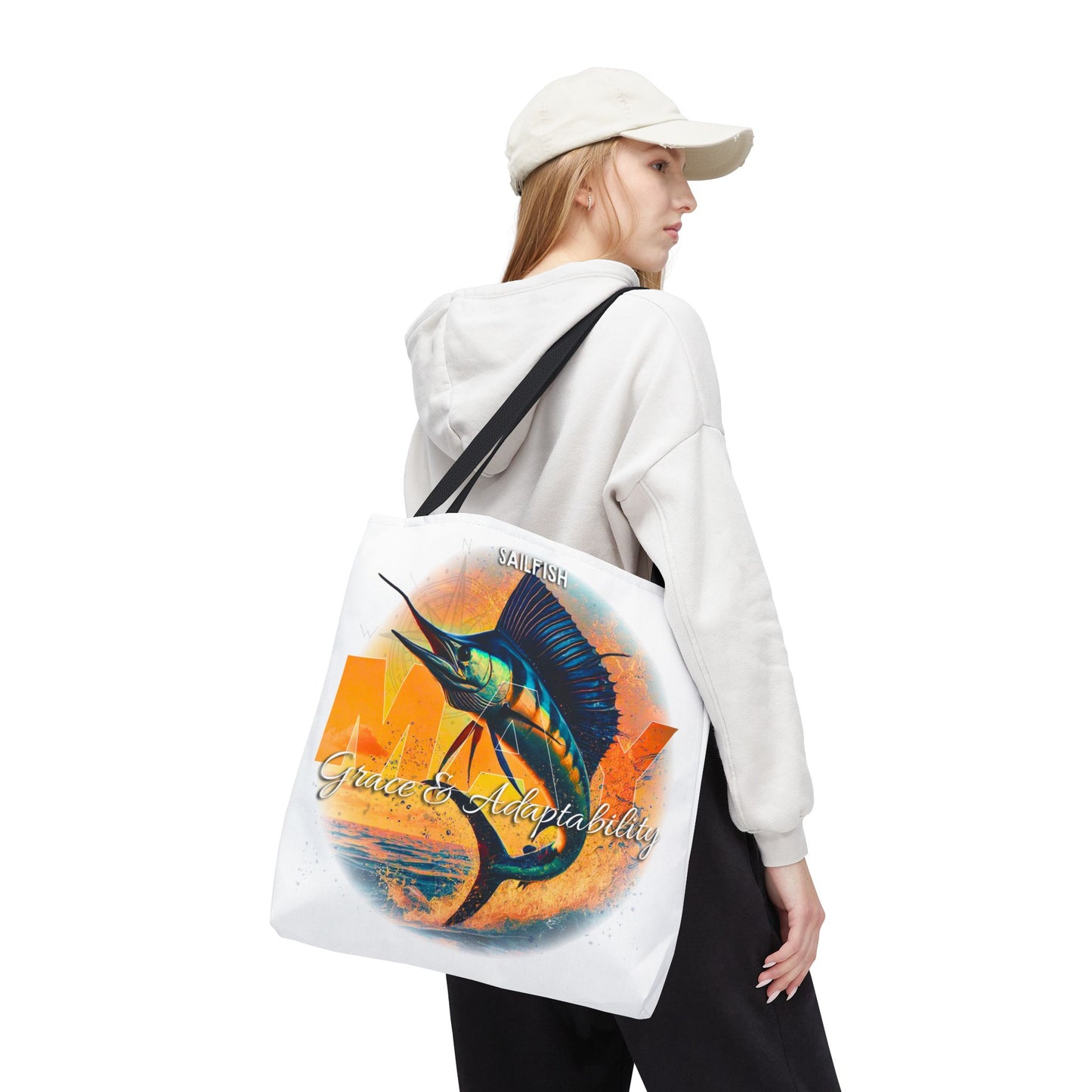 Birth month beach tote with sailfish design and black straps carried by woman in white hoodie and cap