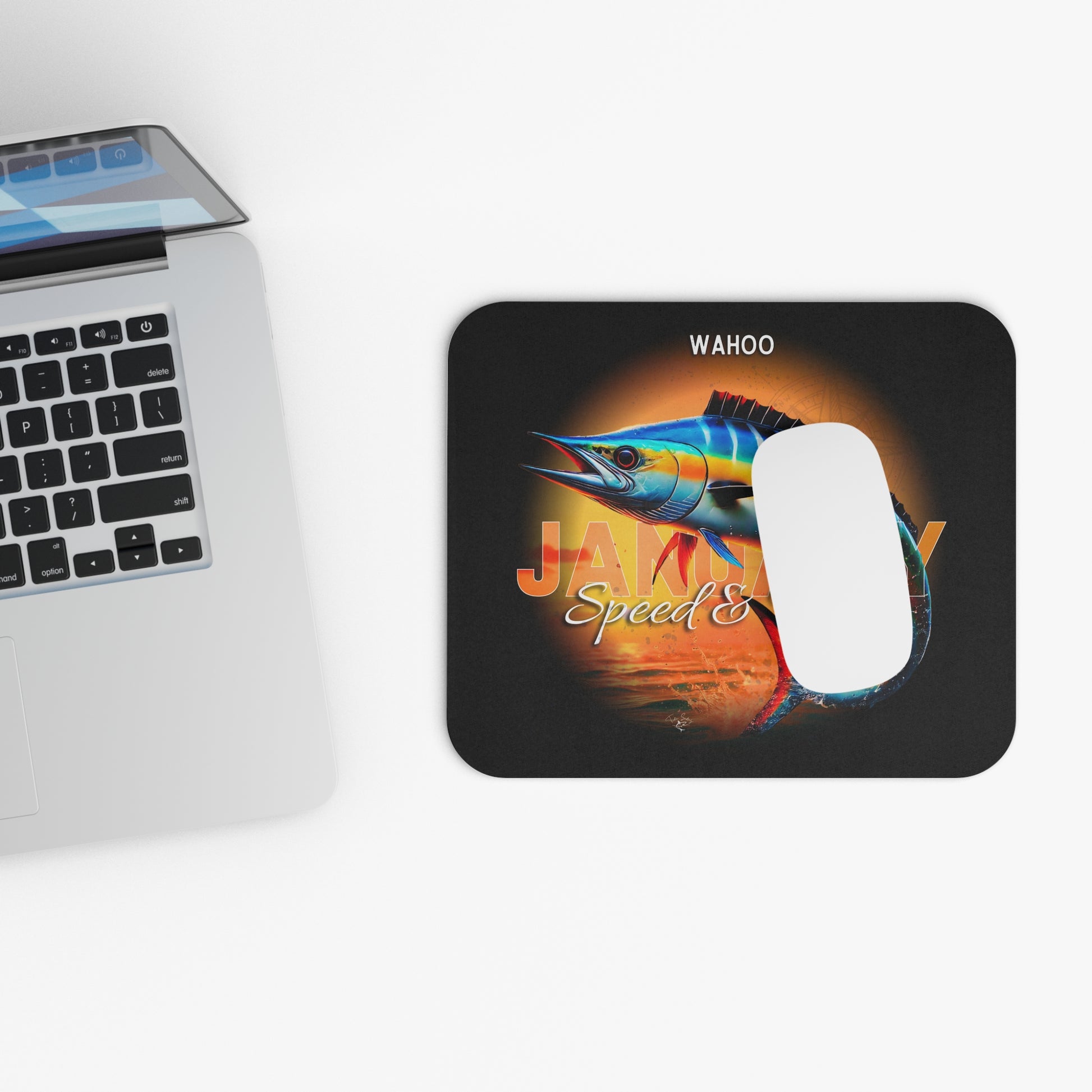 Wahoo print birth month mouse pad with colorful fish design next to laptop