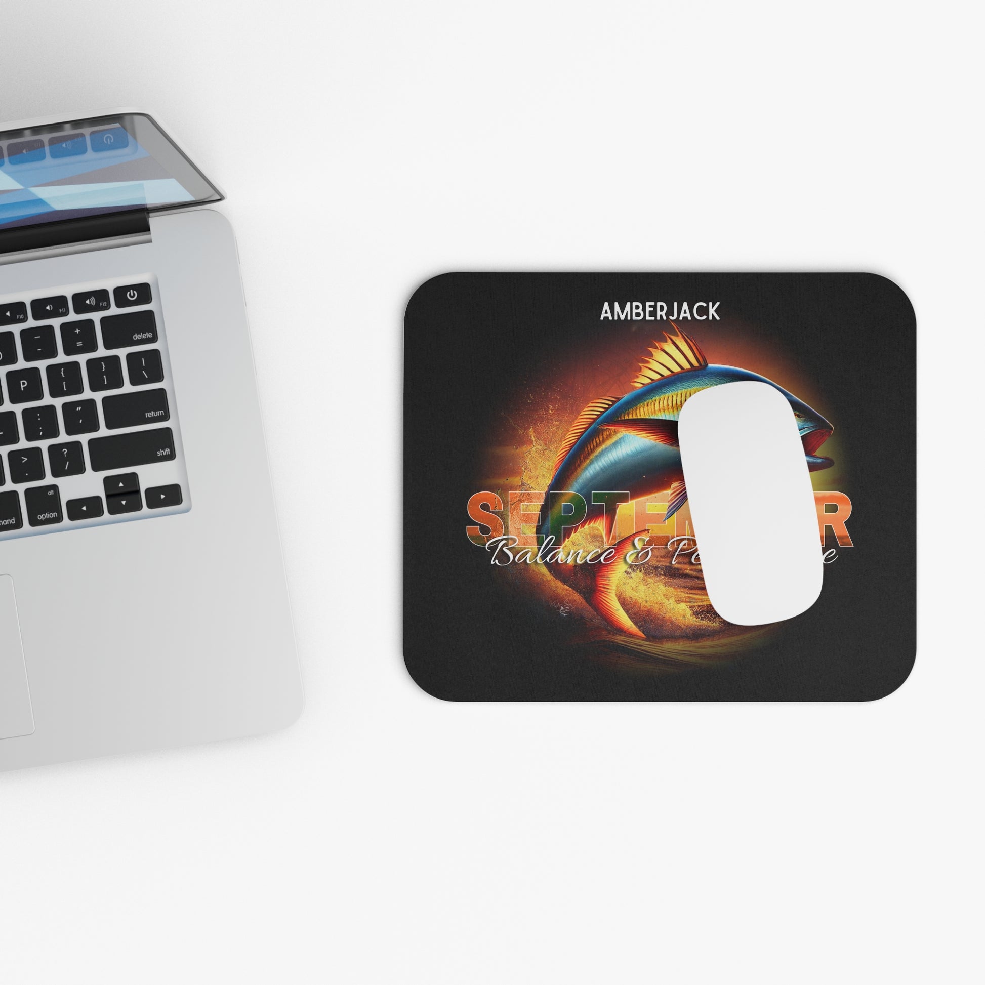 Birth month mouse pad with September design featuring vibrant fish and text next to a laptop keyboard