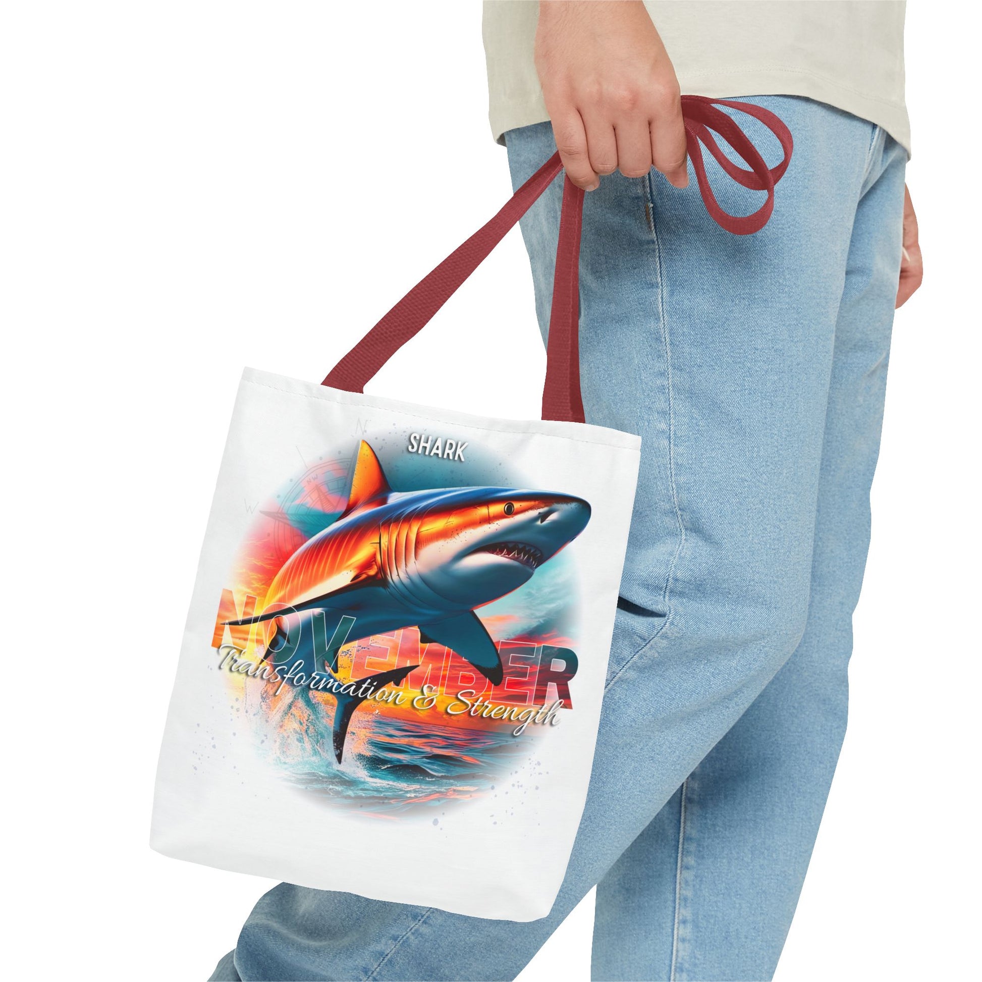 Birth month beach tote with colorful shark design and maroon handles held by person in jeans