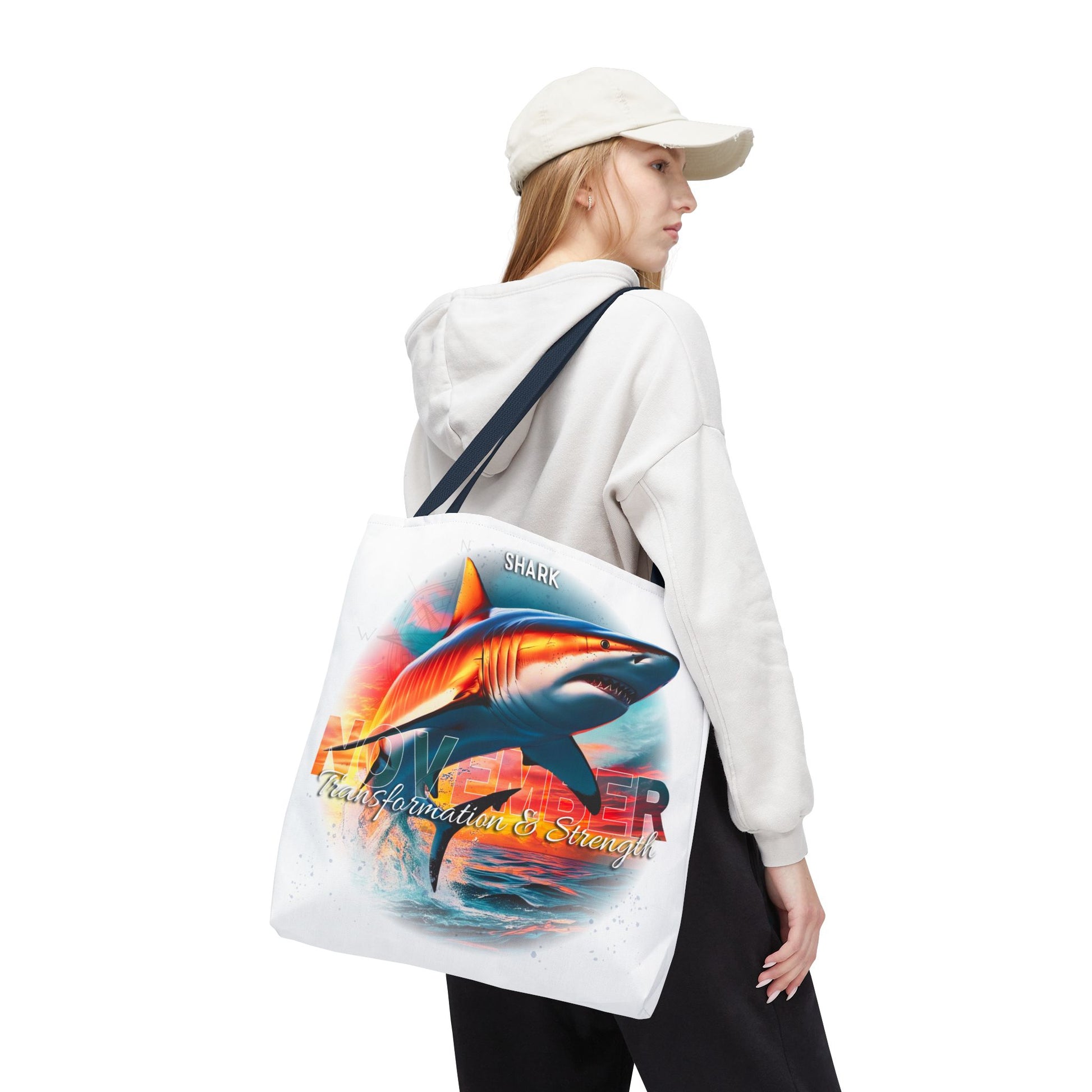 Woman wearing white hoodie and cap carrying birth month beach tote with colorful shark design