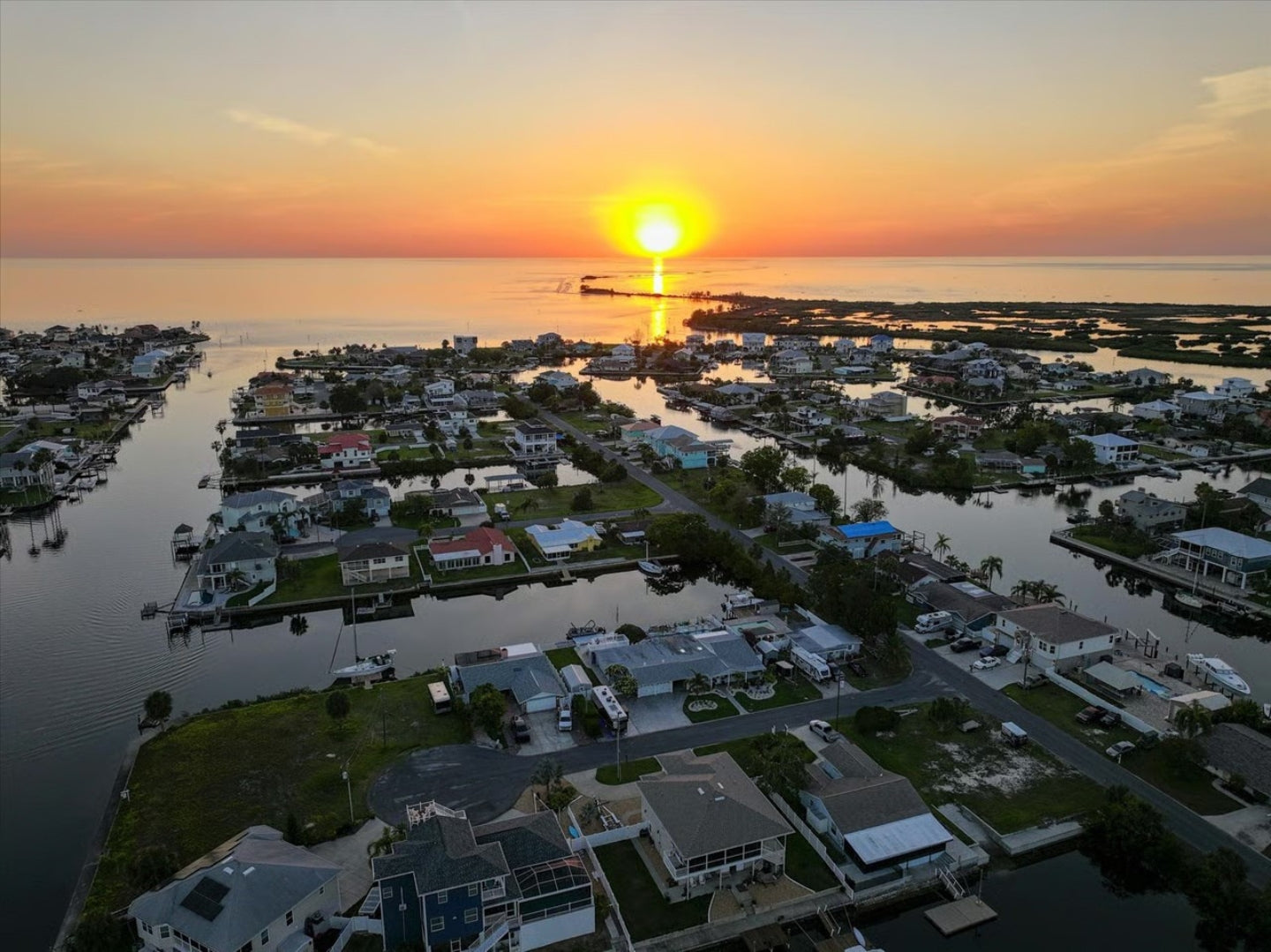 Sunset over a Hernando Beach waterfront residential area with houses and boats.