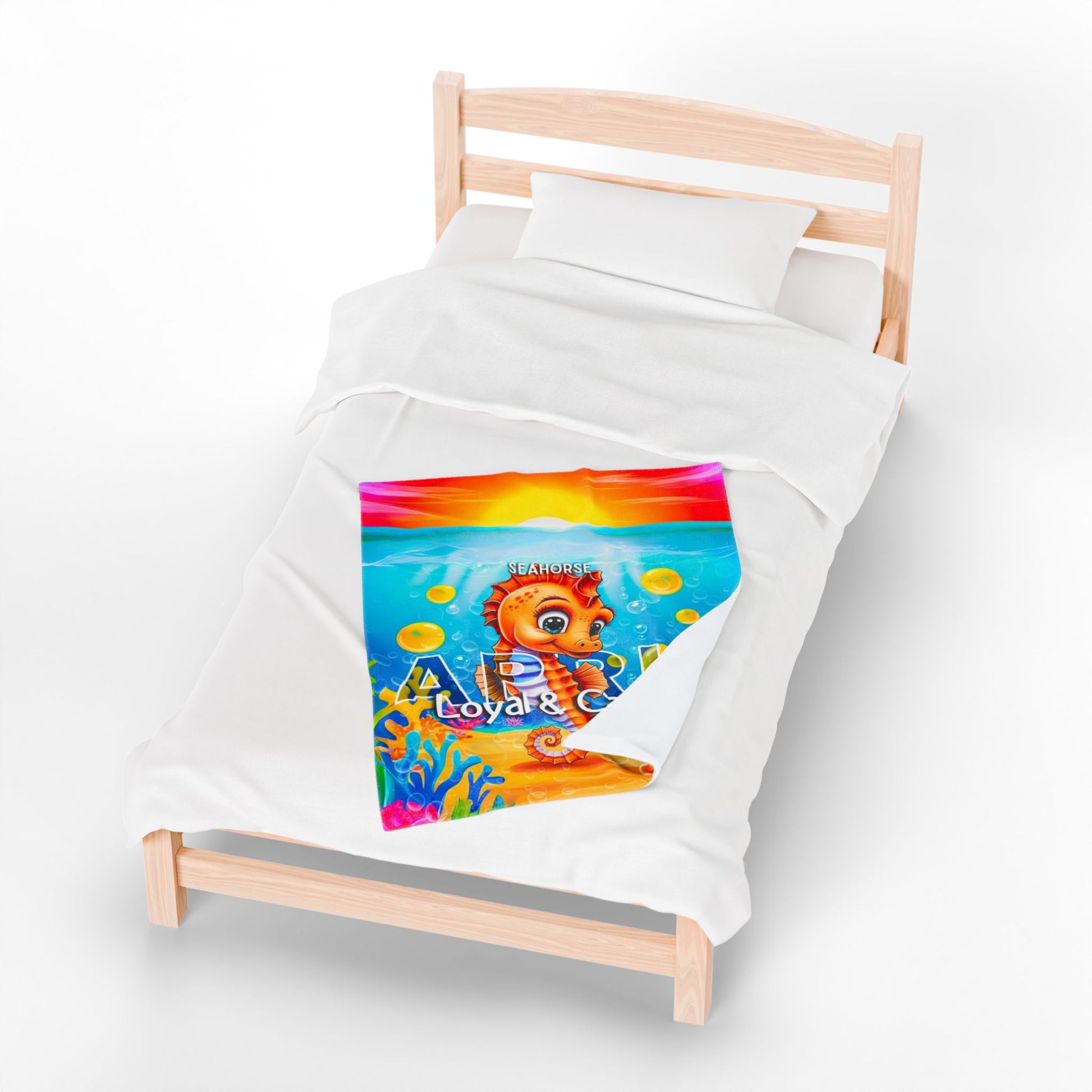 Colorful kids birth month blanket with seahorse design on a wooden twin bed