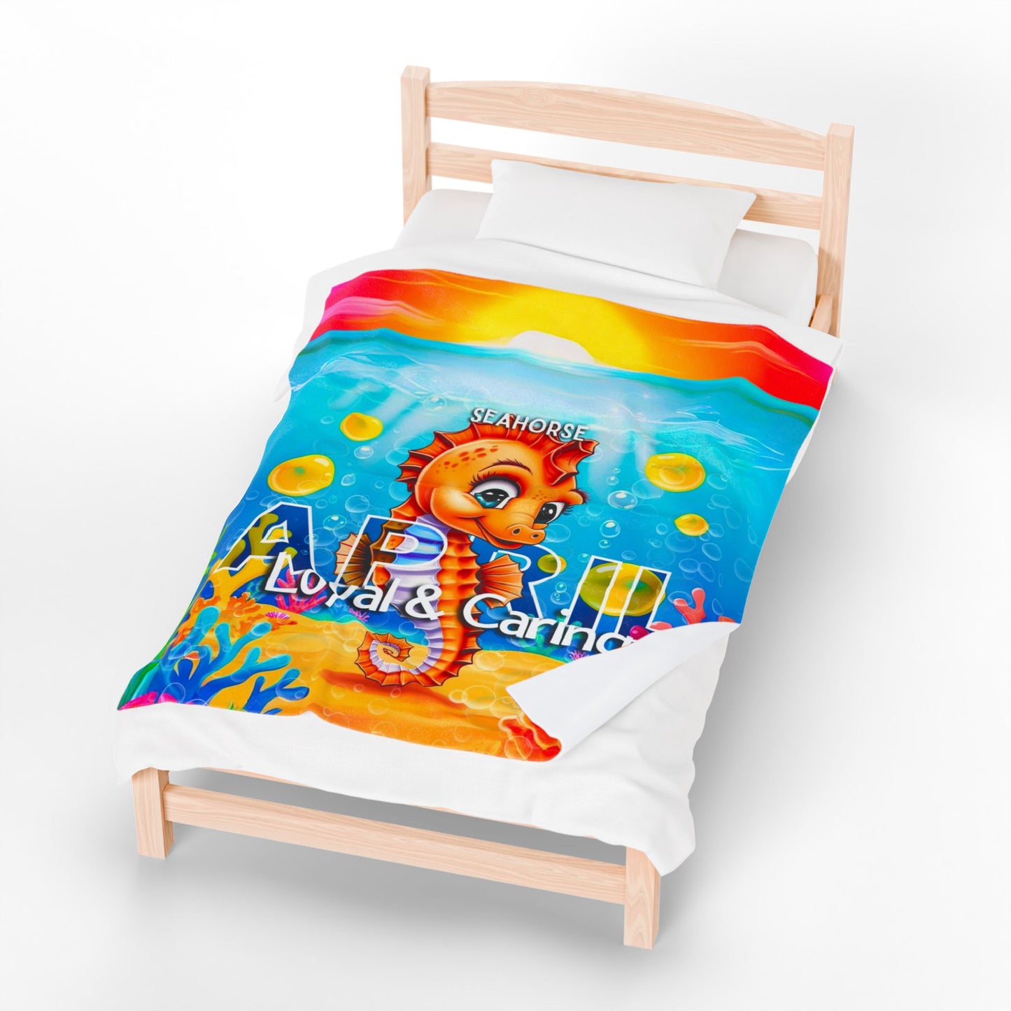 Colorful kids birth month blanket with seahorse design and underwater theme on a wooden bed