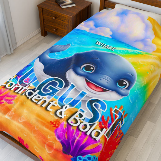 Colorful kids birth month blanket featuring a smiling whale and vibrant underwater design on a bed