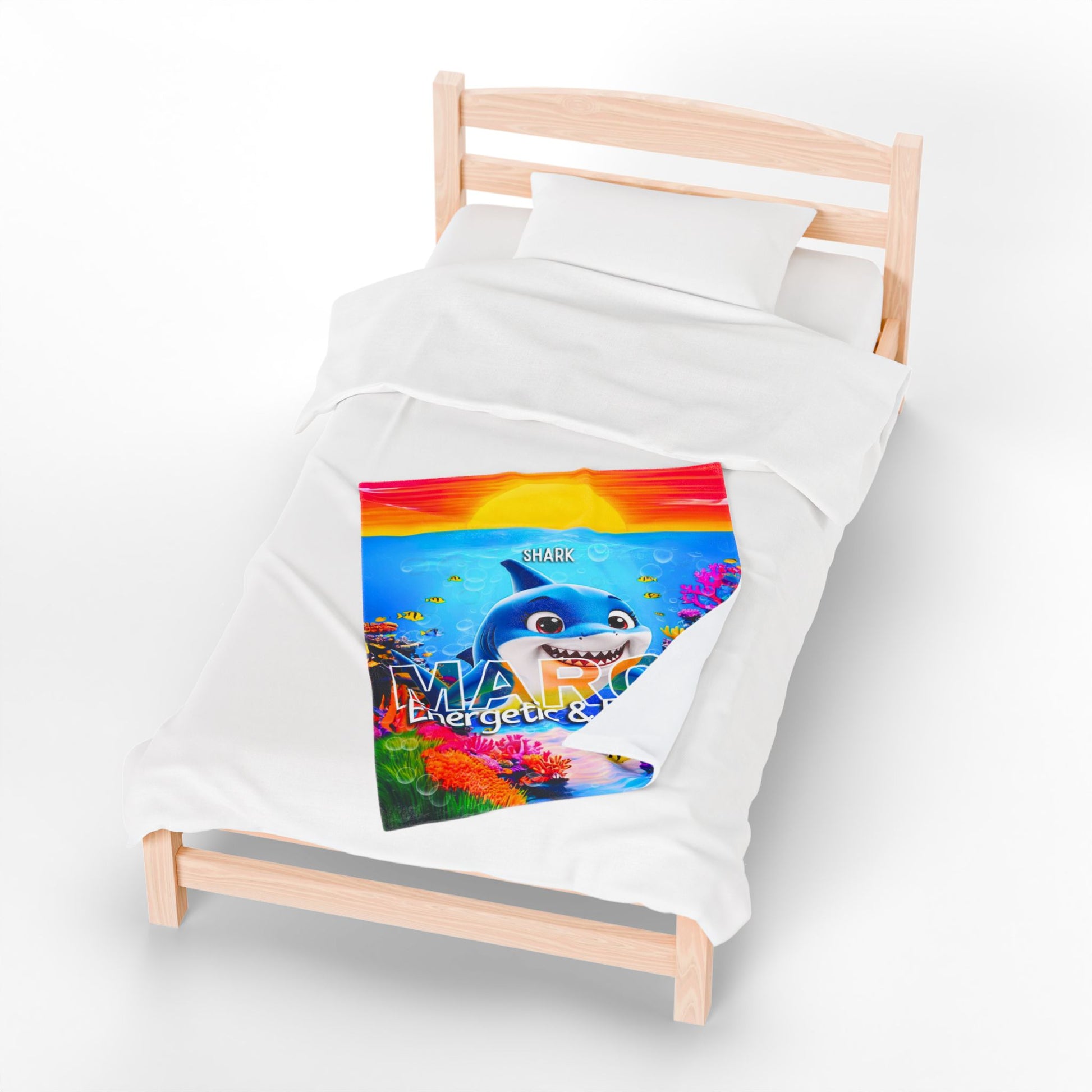 Kids birth month blanket with colorful shark design on a small wooden bed