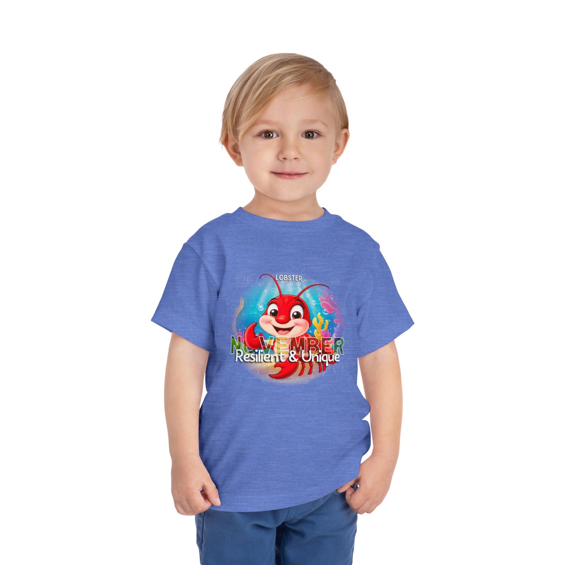 Toddler wearing a blue kids birth month tshirt with a colorful lobster November design