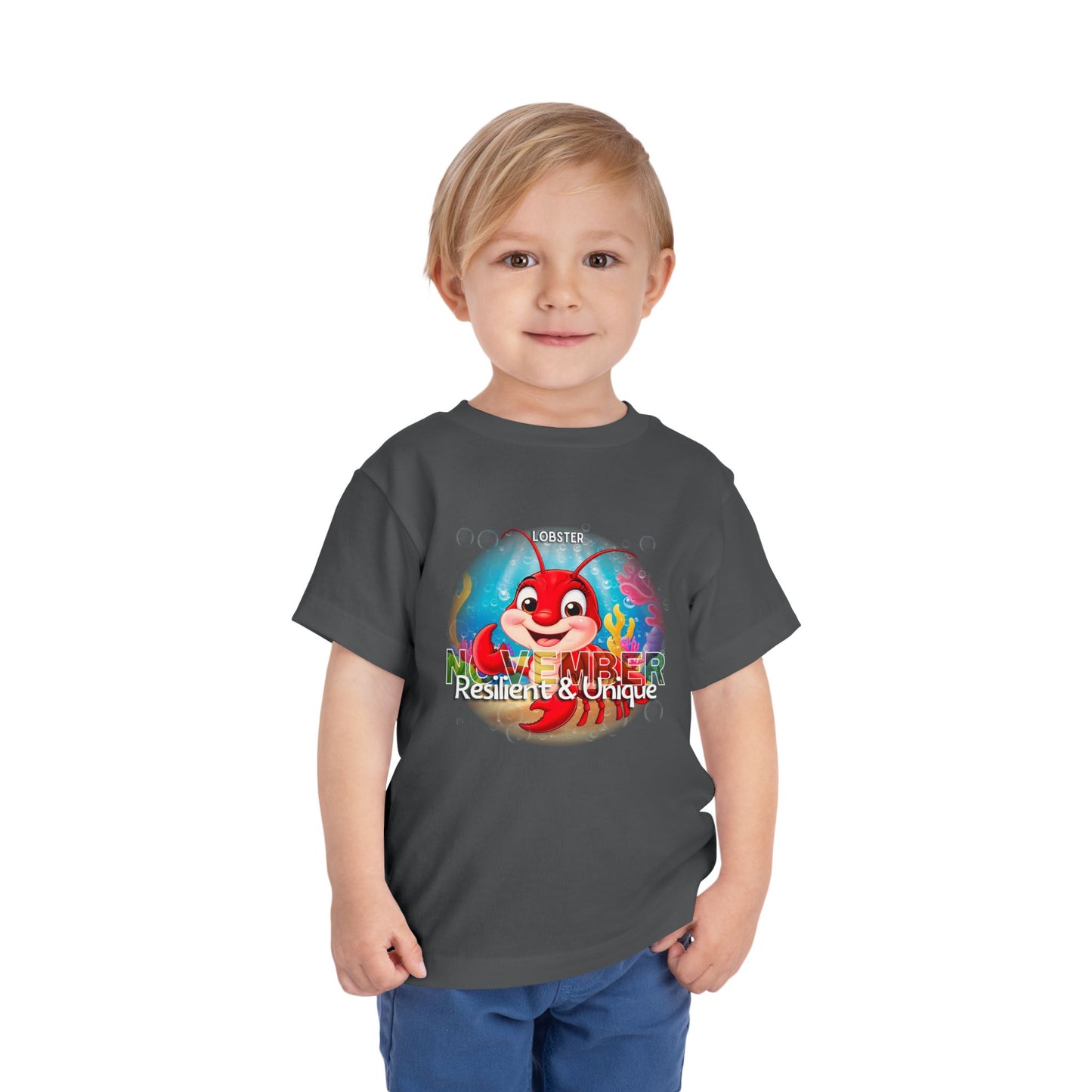 Toddler wearing a kids birth month tshirt featuring a November lobster design with resilient and unique text