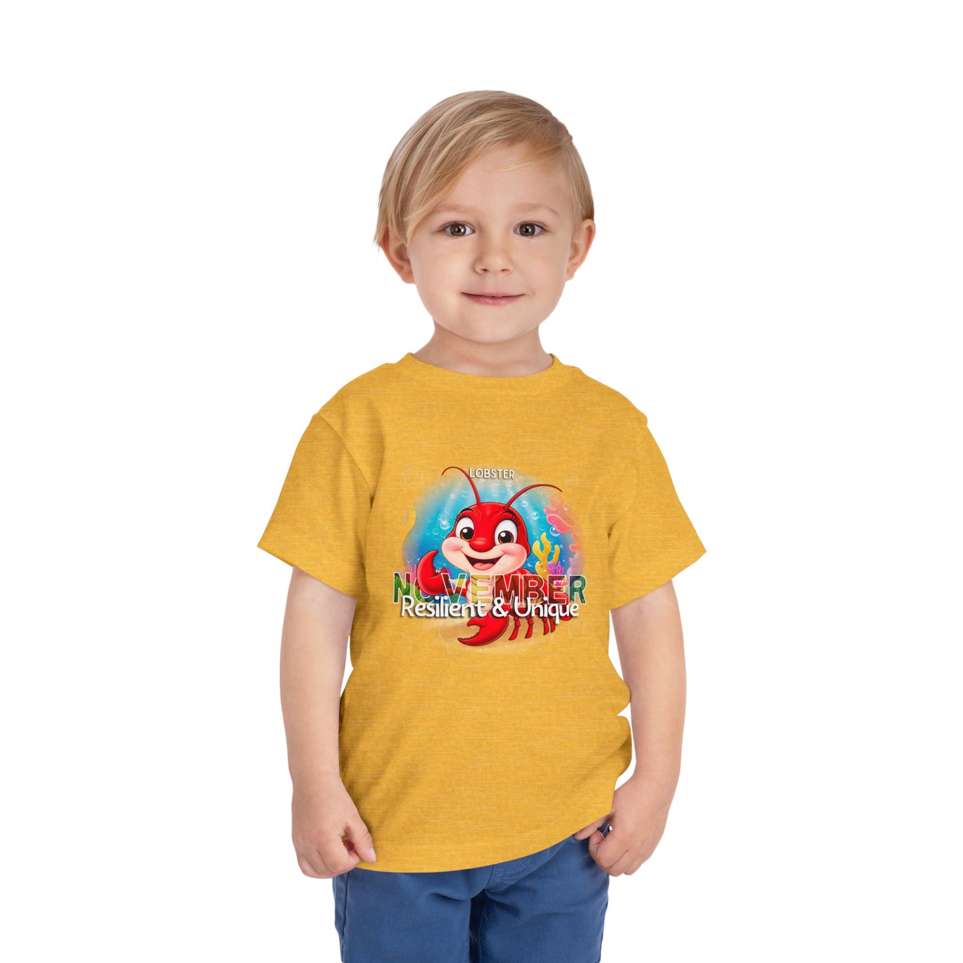 Child wearing yellow kids birth month tshirt with November crab graphic and resilient unique text