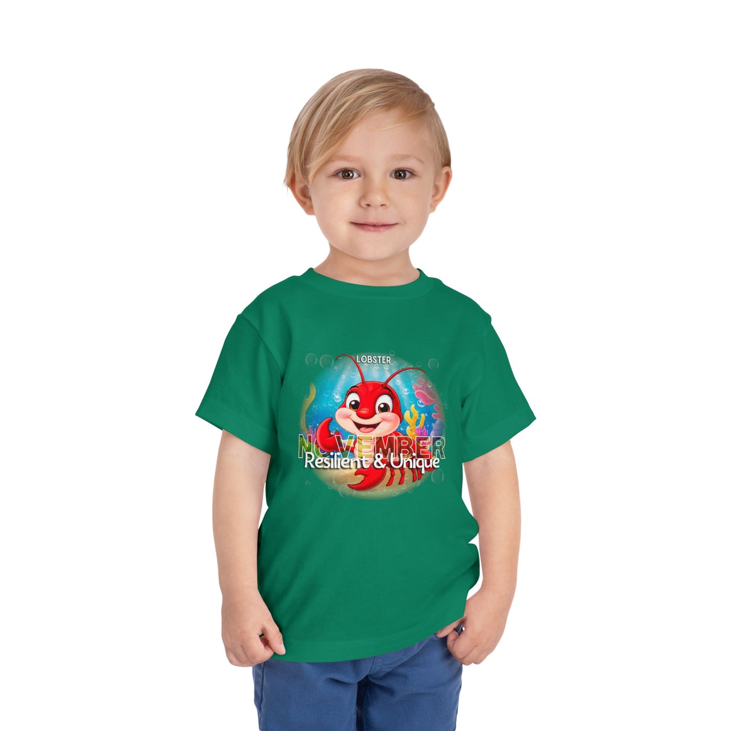 Green kids birth month tshirt featuring a red lobster cartoon and November text worn by a smiling toddler