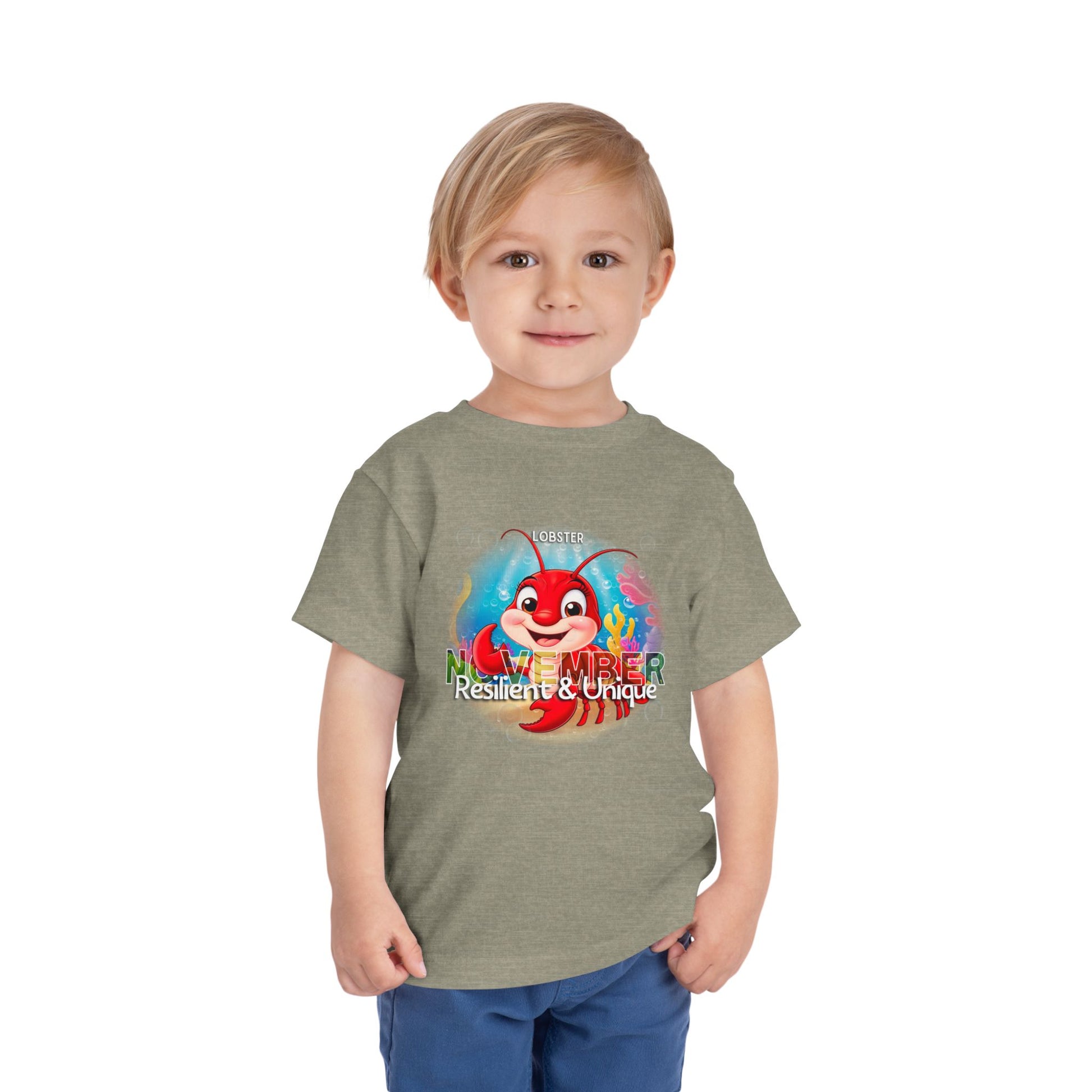 Toddler wearing kids birth month tshirt with November lobster design and Resilient Unique text