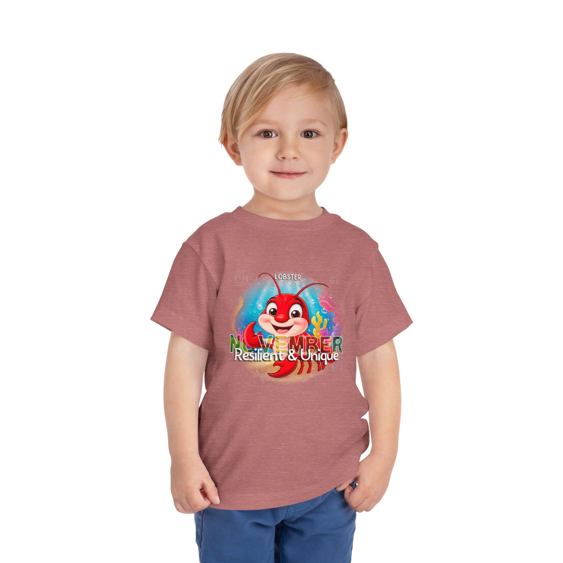 Young boy wearing a kids birth month tshirt with November lobster design in red