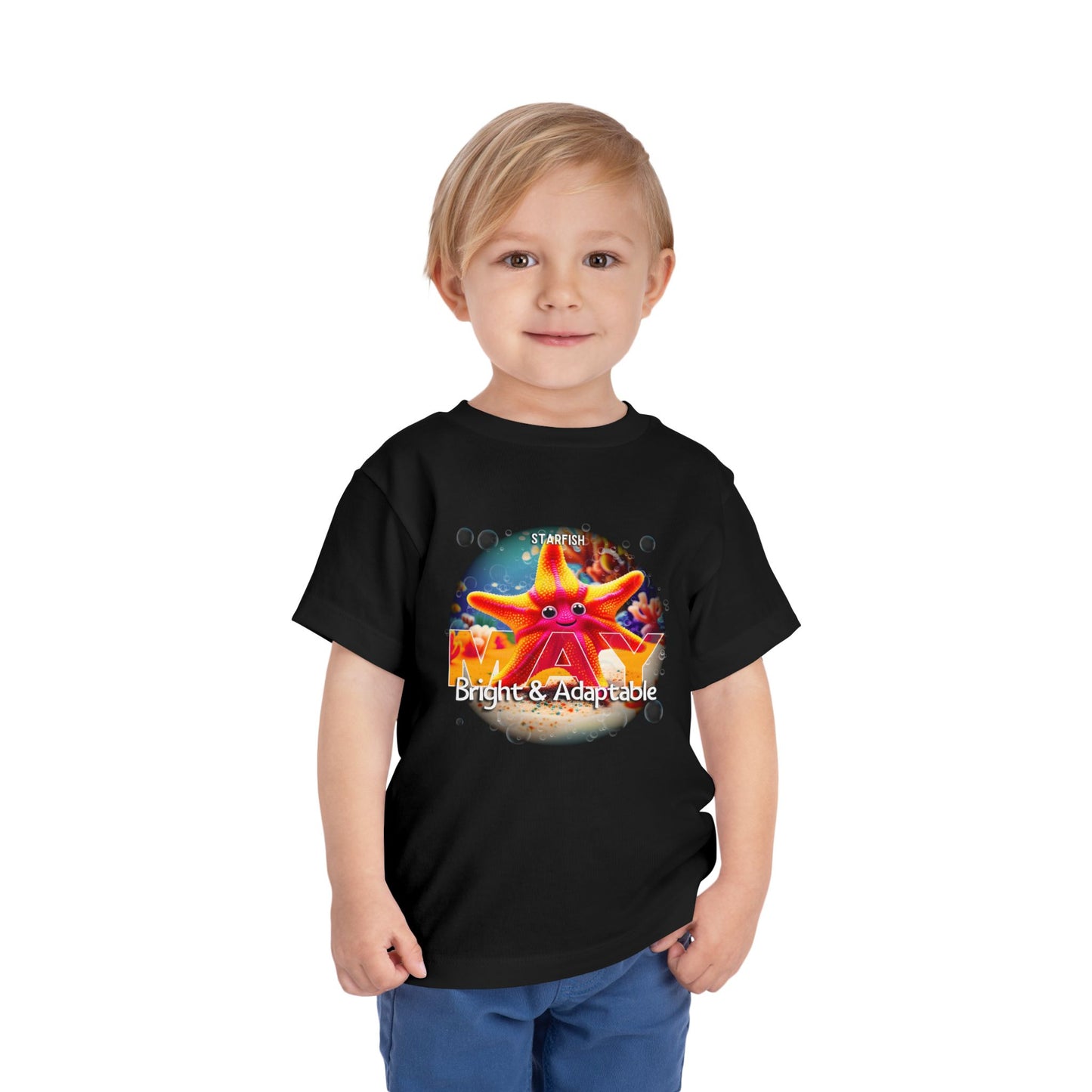 Toddler wearing a black kids birth month tshirt with a colorful starfish design and text bright and adaptable