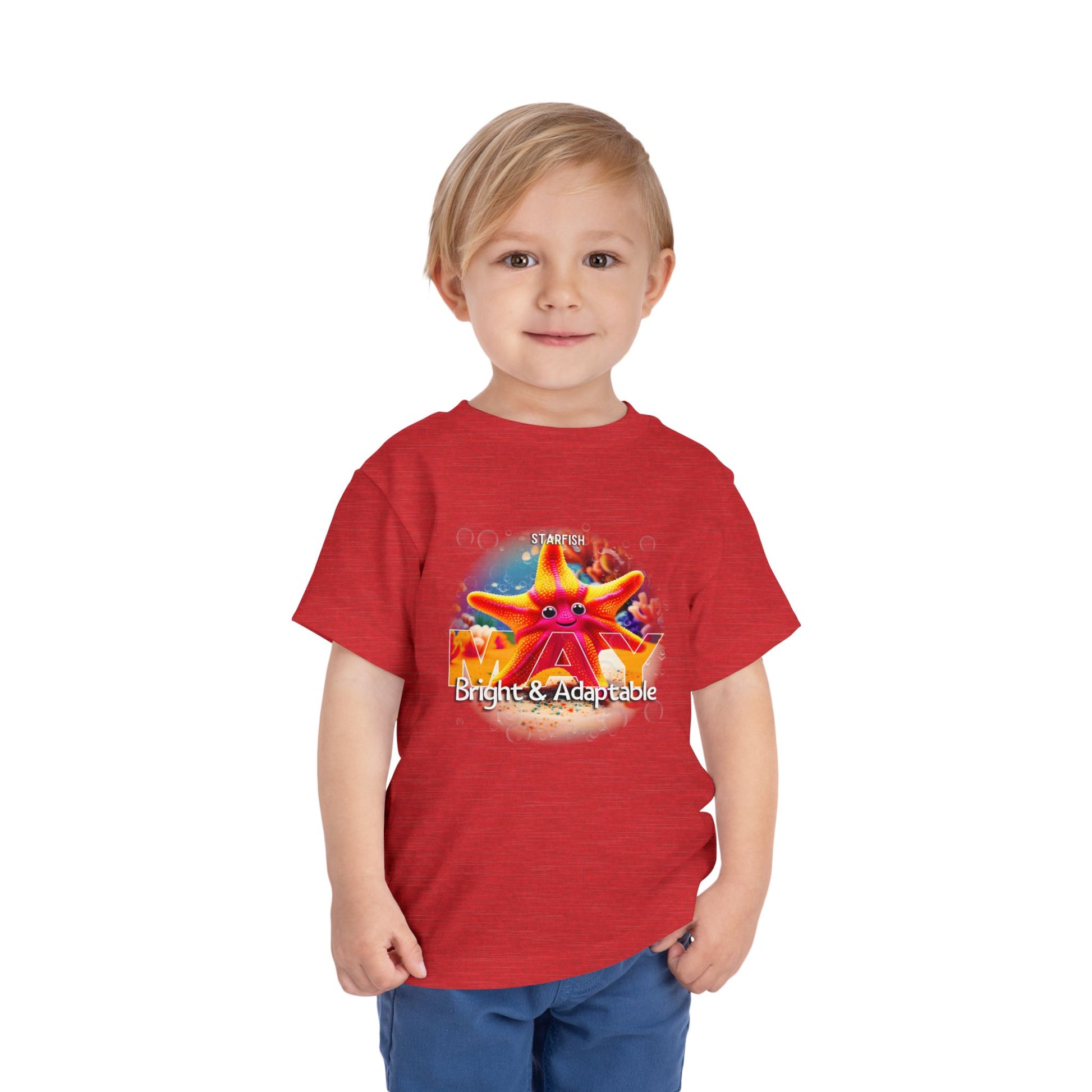 Toddler wearing a red kids birth month tshirt featuring a colorful starfish design with bright and adaptable text