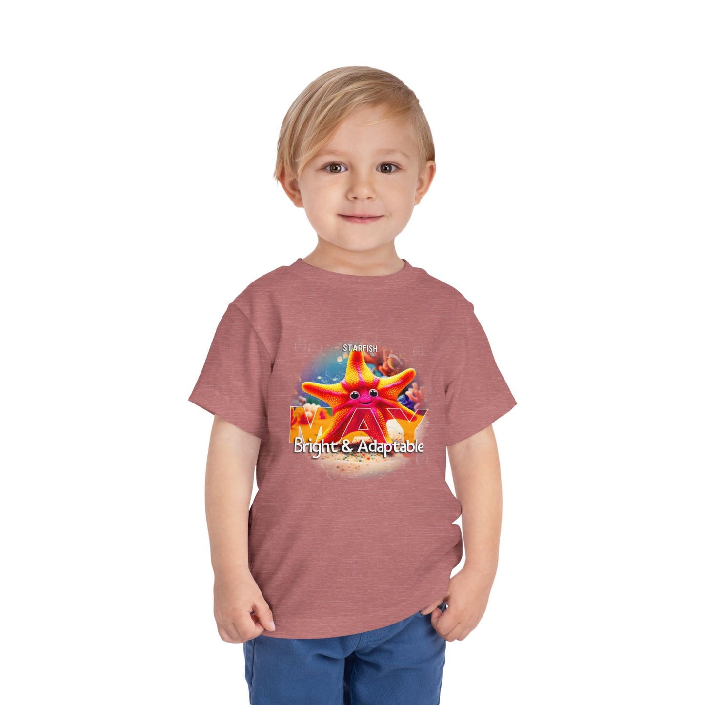 Little boy wearing a kids birth month tshirt with a colorful starfish design and text Bright Adaptable