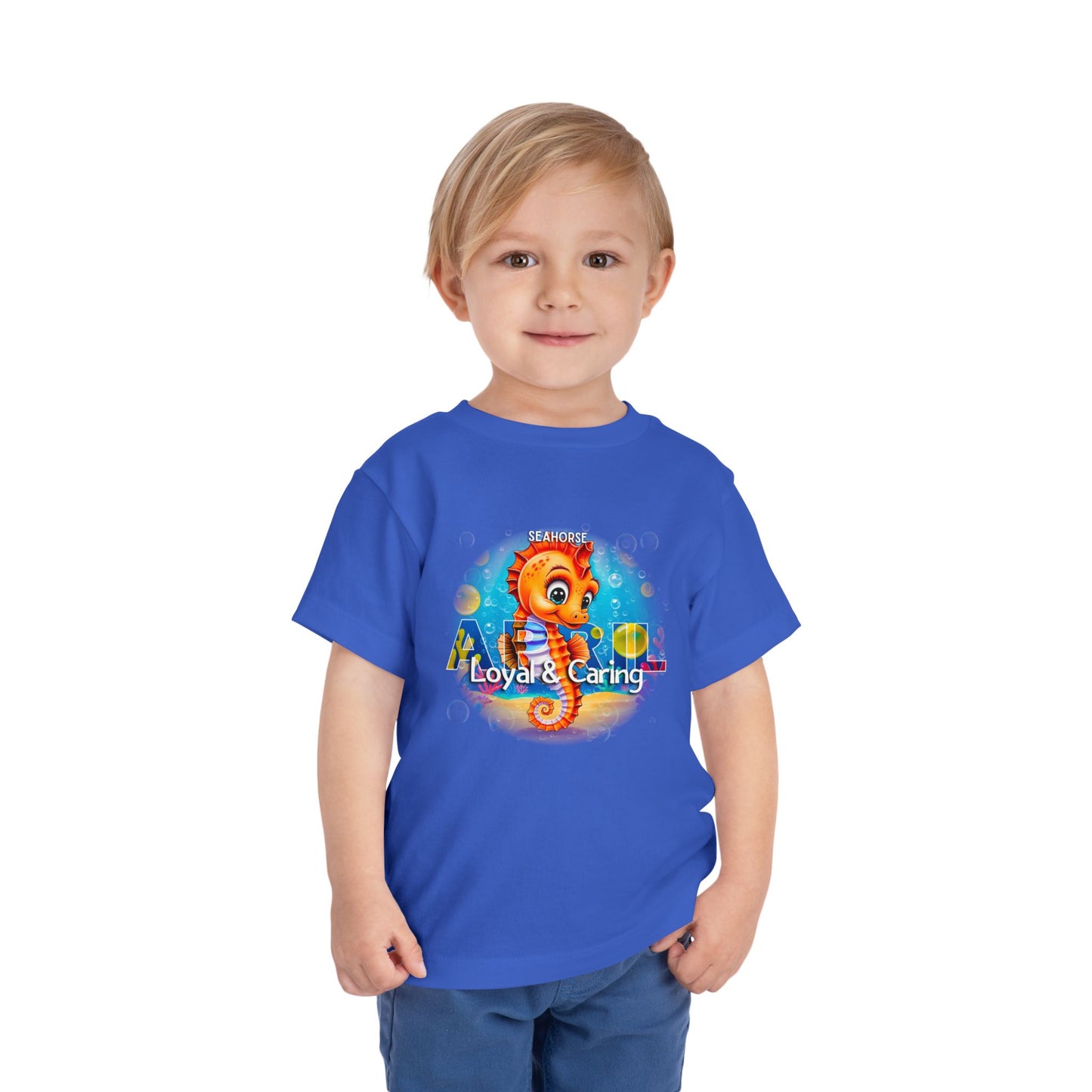 Toddler wearing blue kids birth month tshirt with colorful seahorse design and loyal caring text