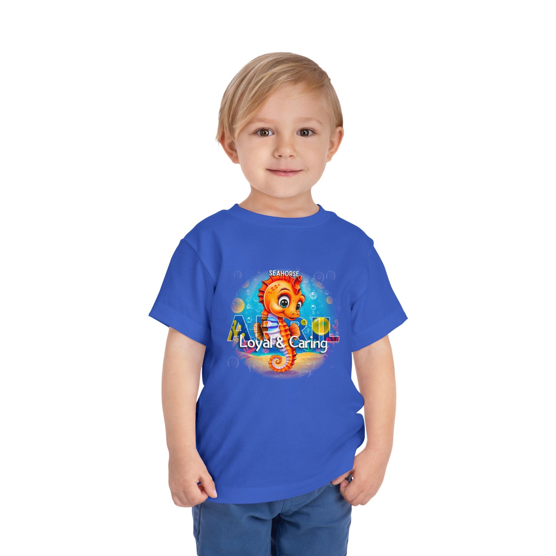 Toddler wearing blue kids birth month tshirt with colorful seahorse design and loyal caring text