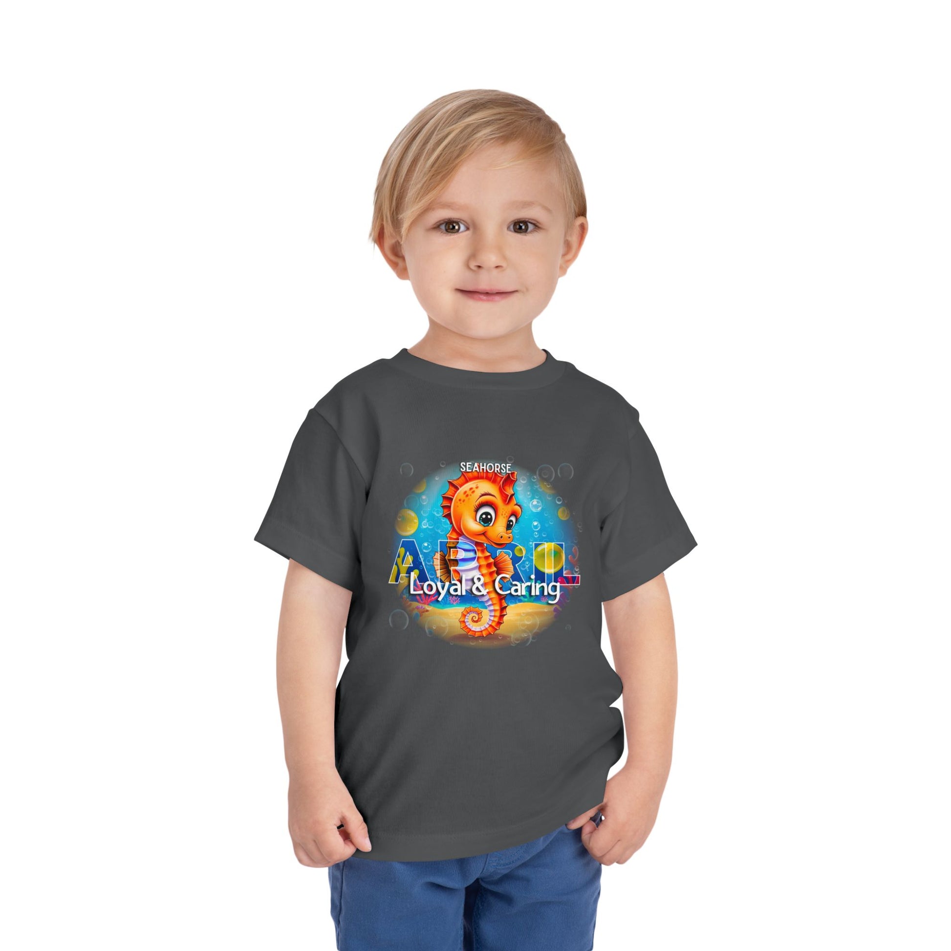 Child wearing a gray kids birth month tshirt with colorful seahorse design and loyal caring text