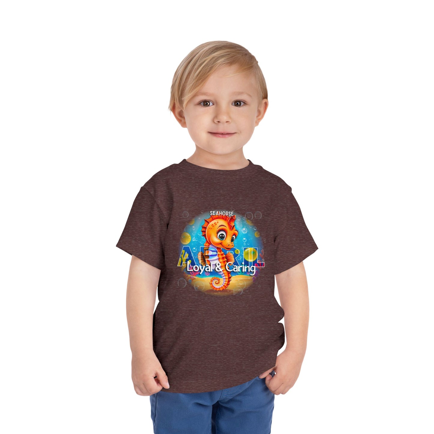 Young boy wearing kids birth month tshirt with colorful seahorse design and loyal caring text