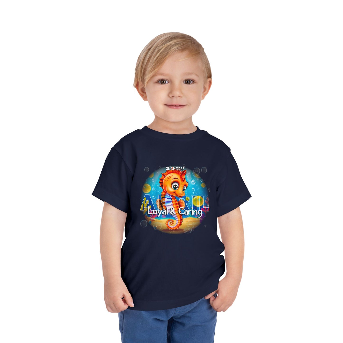 Toddler wearing navy kids birth month tshirt with colorful seahorse design and loyal caring text