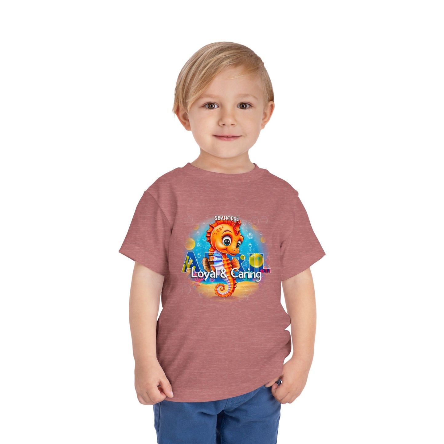 Toddler wearing kids birth month tshirt with colorful seahorse design and loyal caring text