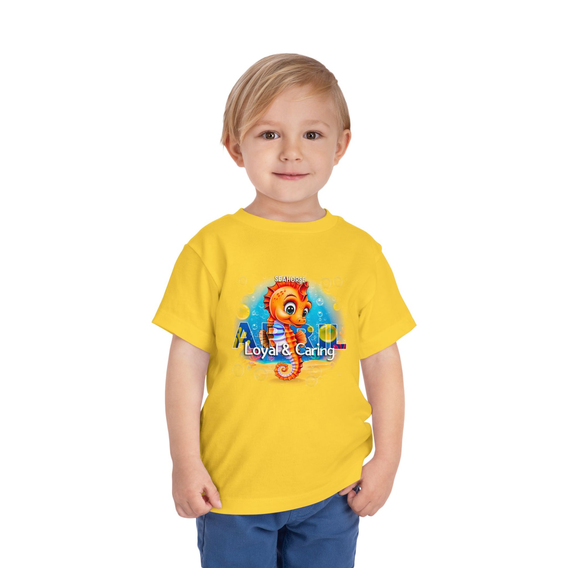 Yellow kids birth month tshirt with cartoon seahorse design worn by smiling toddler