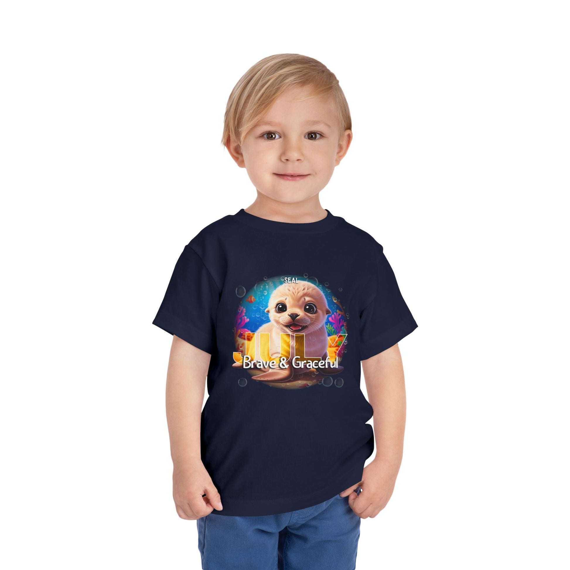 Toddler wearing navy kids birth month tshirt with colorful sea otter graphic and brave and graceful text