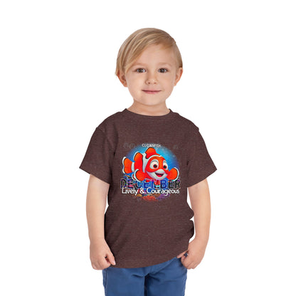 Toddler wearing a kids birth month tshirt with December clownfish design in brown