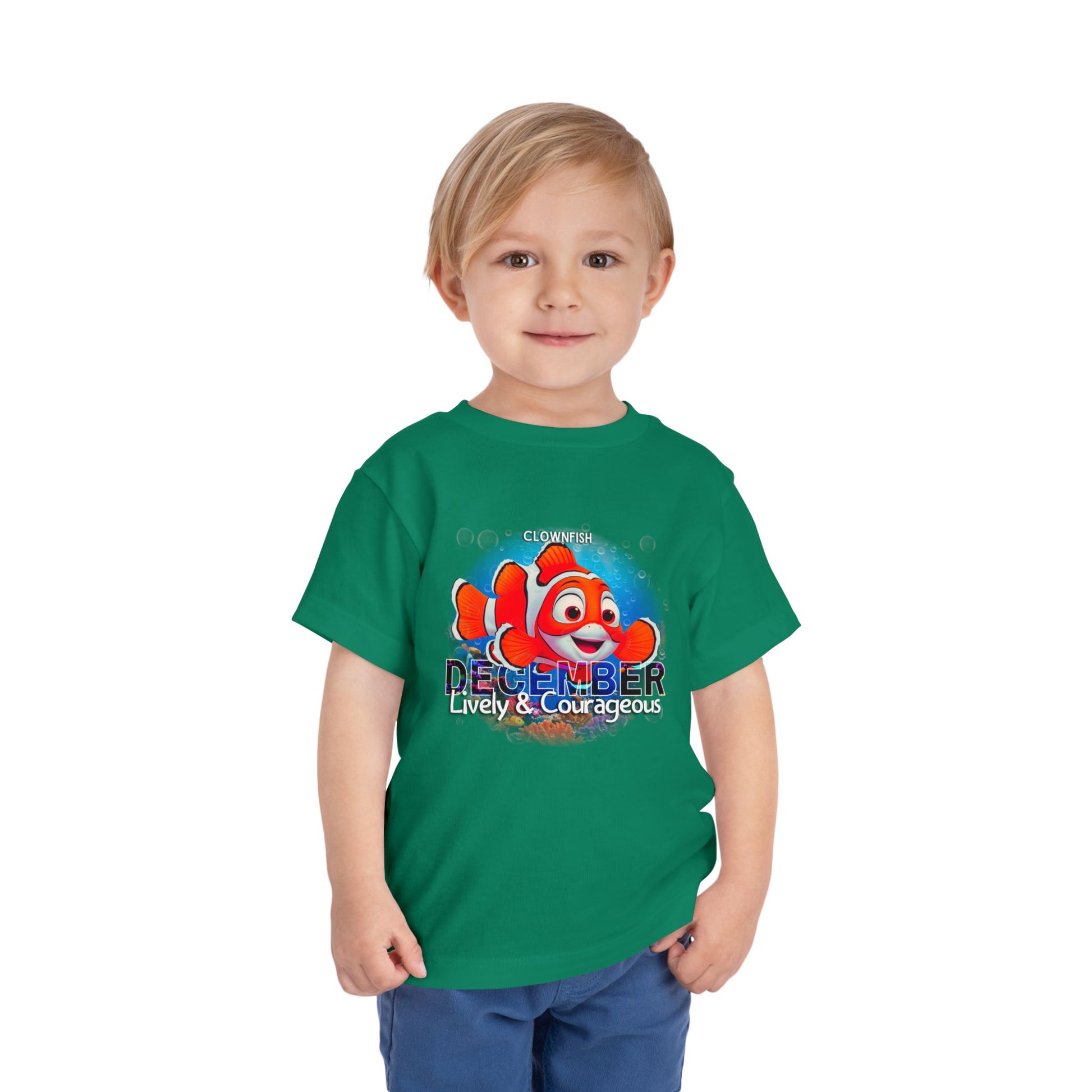 Child wearing green kids birth month tshirt with colorful December clownfish design