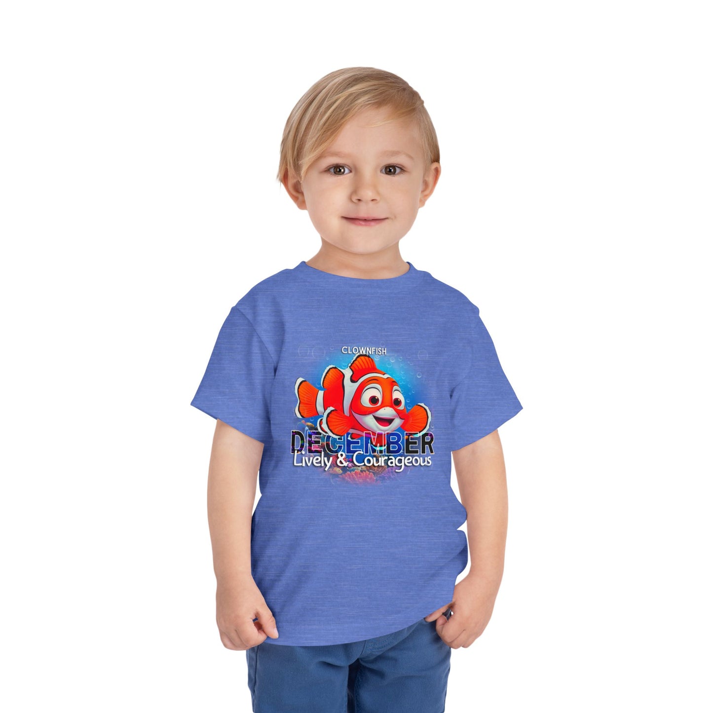Toddler wearing a blue kids birth month tshirt with December clownfish design and lively courageous text