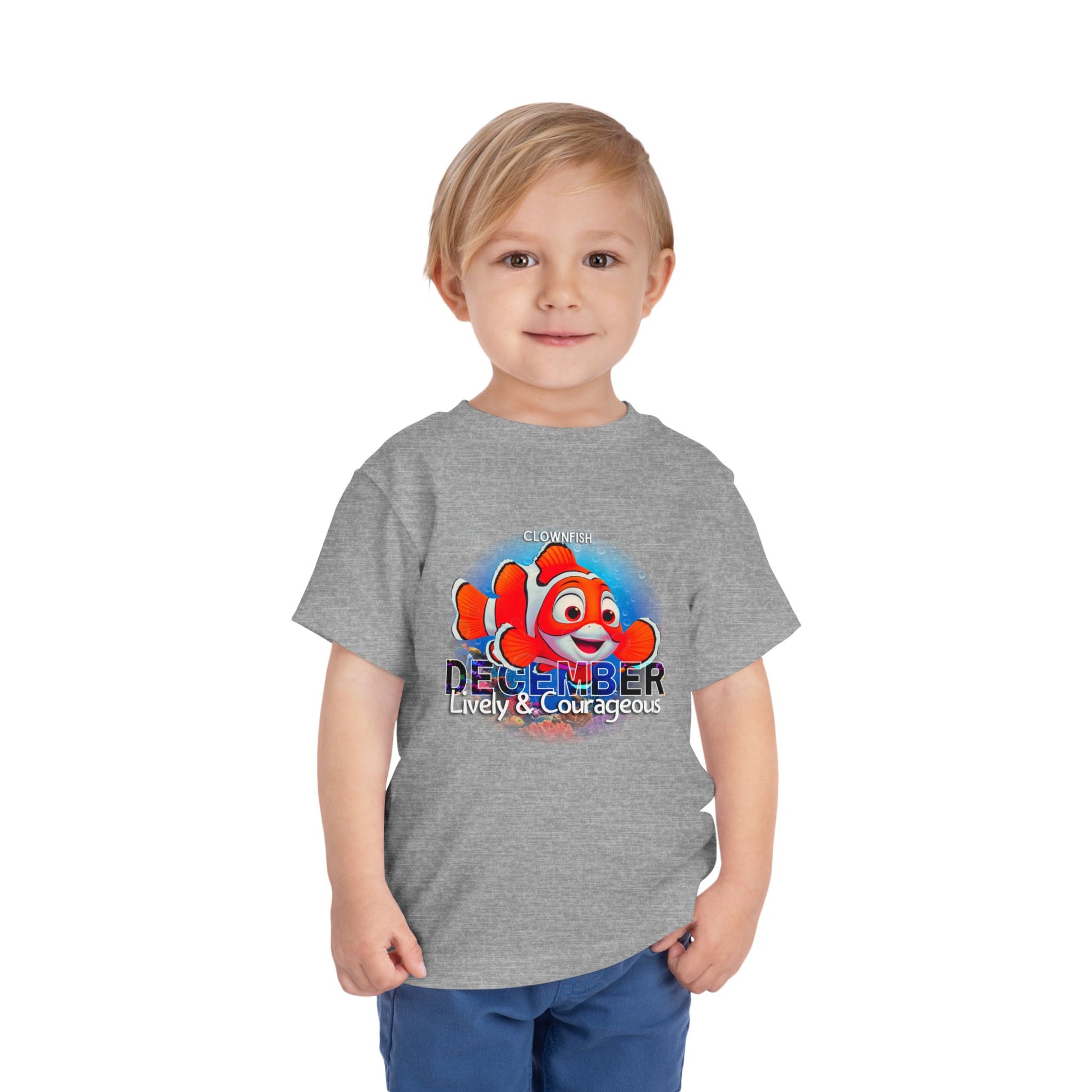 Child wearing a grey kids birth month tshirt with colorful December clownfish design 
