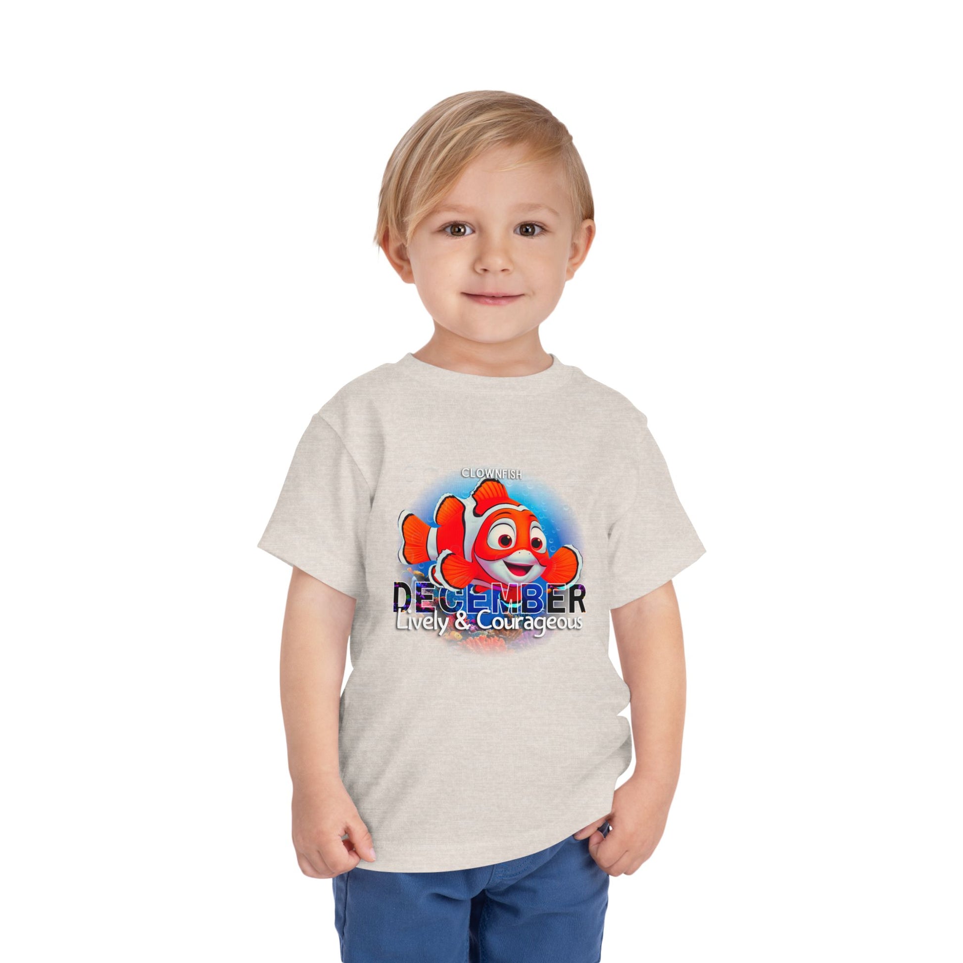 Kids birth month tshirt featuring lively December clownfish design on beige shirt