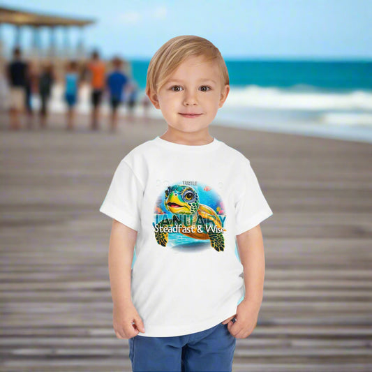 Child wearing a white kids birth month tshirt featuring a turtle design and January text at the beach