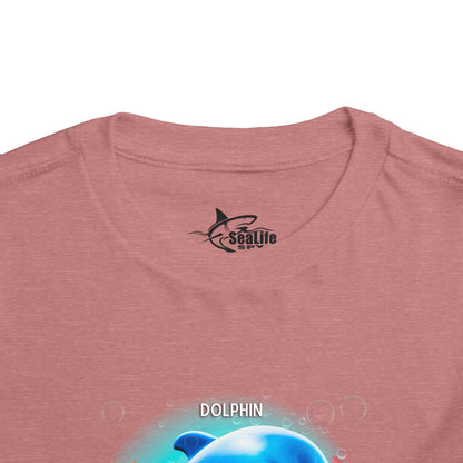 Kids birth month tshirt with dolphin graphic on pink fabric close up