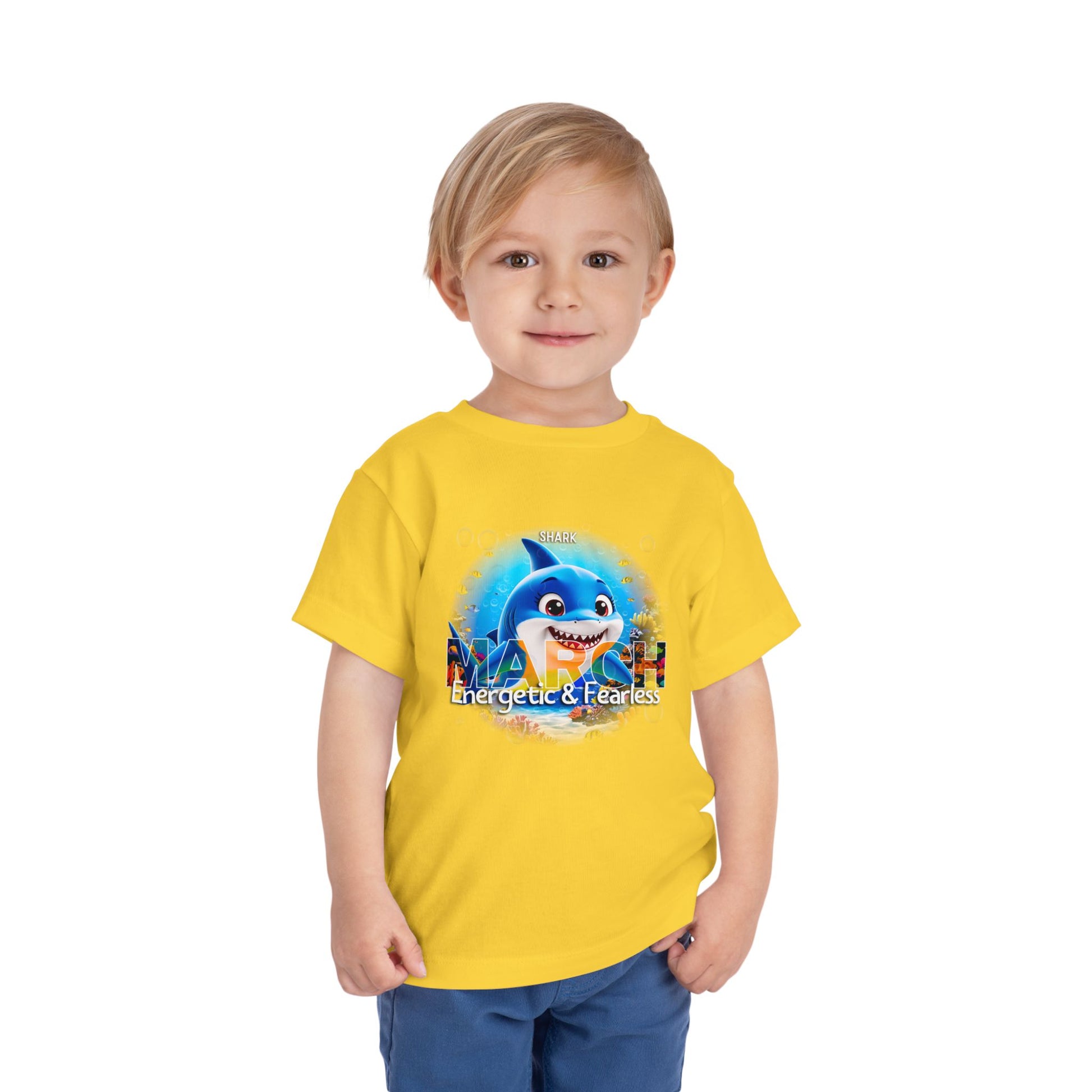 Young boy wearing a yellow kids birth month tshirt with a March shark design and fearless text