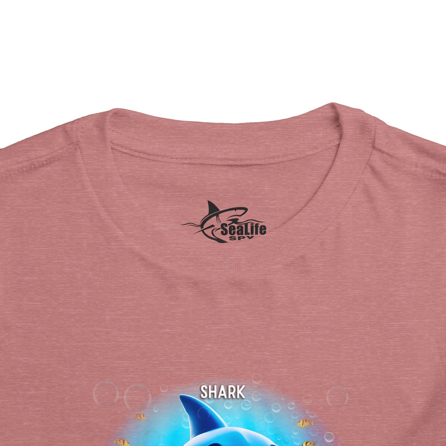 Kids birth month tshirt with colorful shark design on pink fabric close up