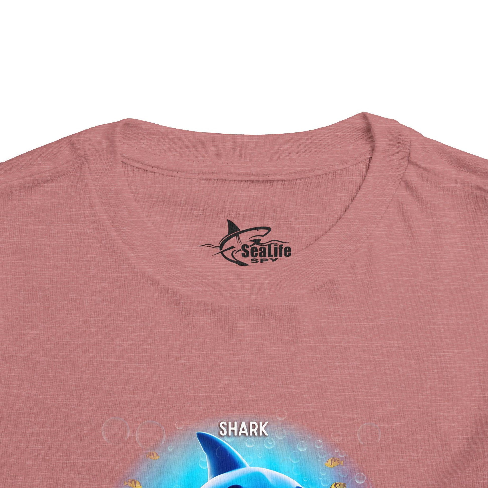 Kids birth month tshirt with colorful shark design on pink fabric close up