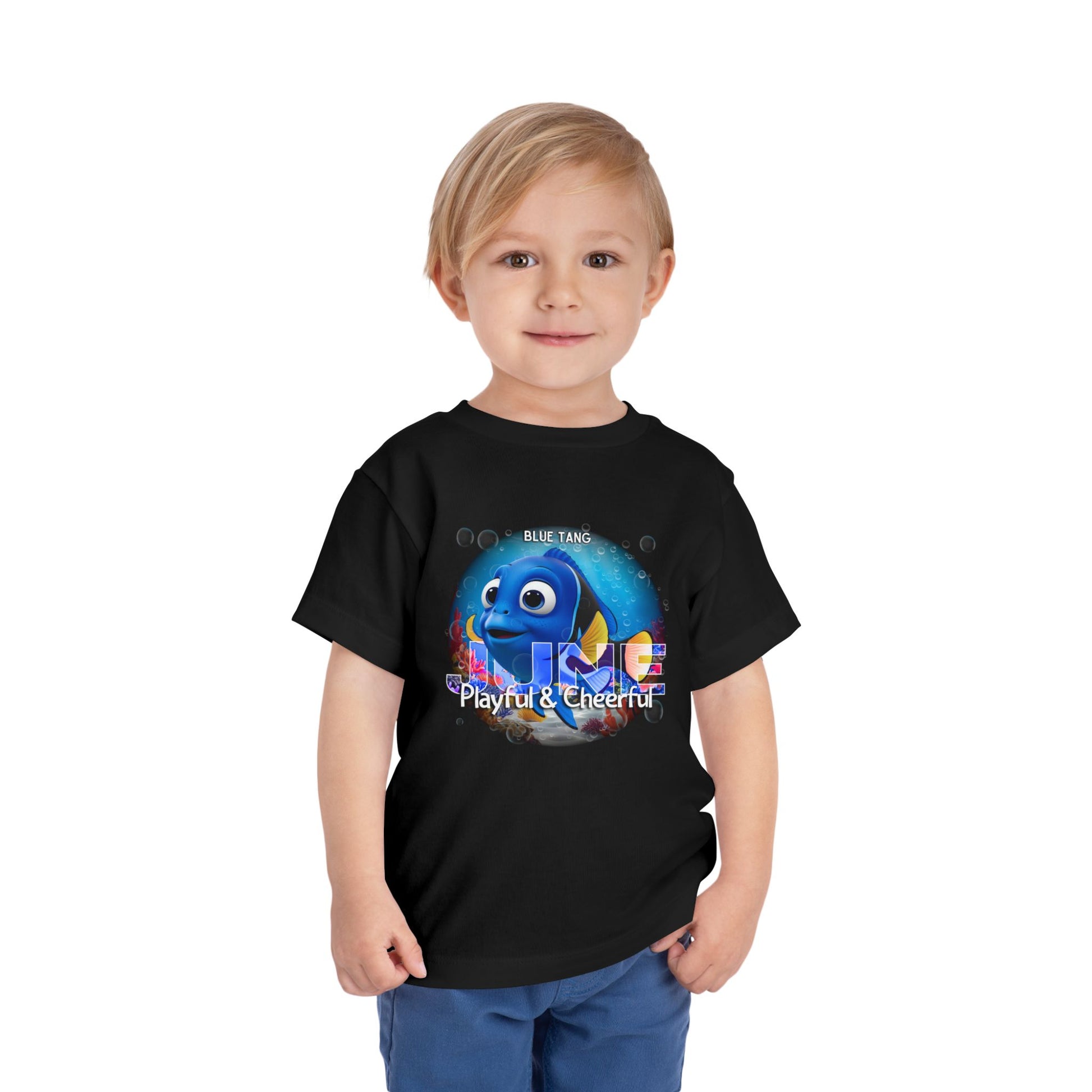 Toddler wearing black kids birth month tshirt with playful blue tang graphic and colorful text