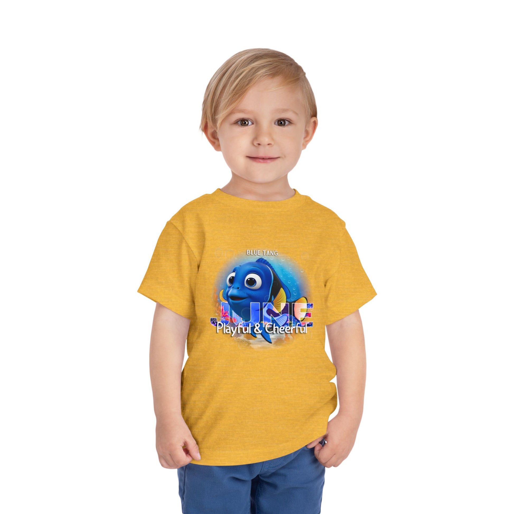 Toddler wearing yellow kids birth month tshirt with playful blue fish graphic and cheerful design