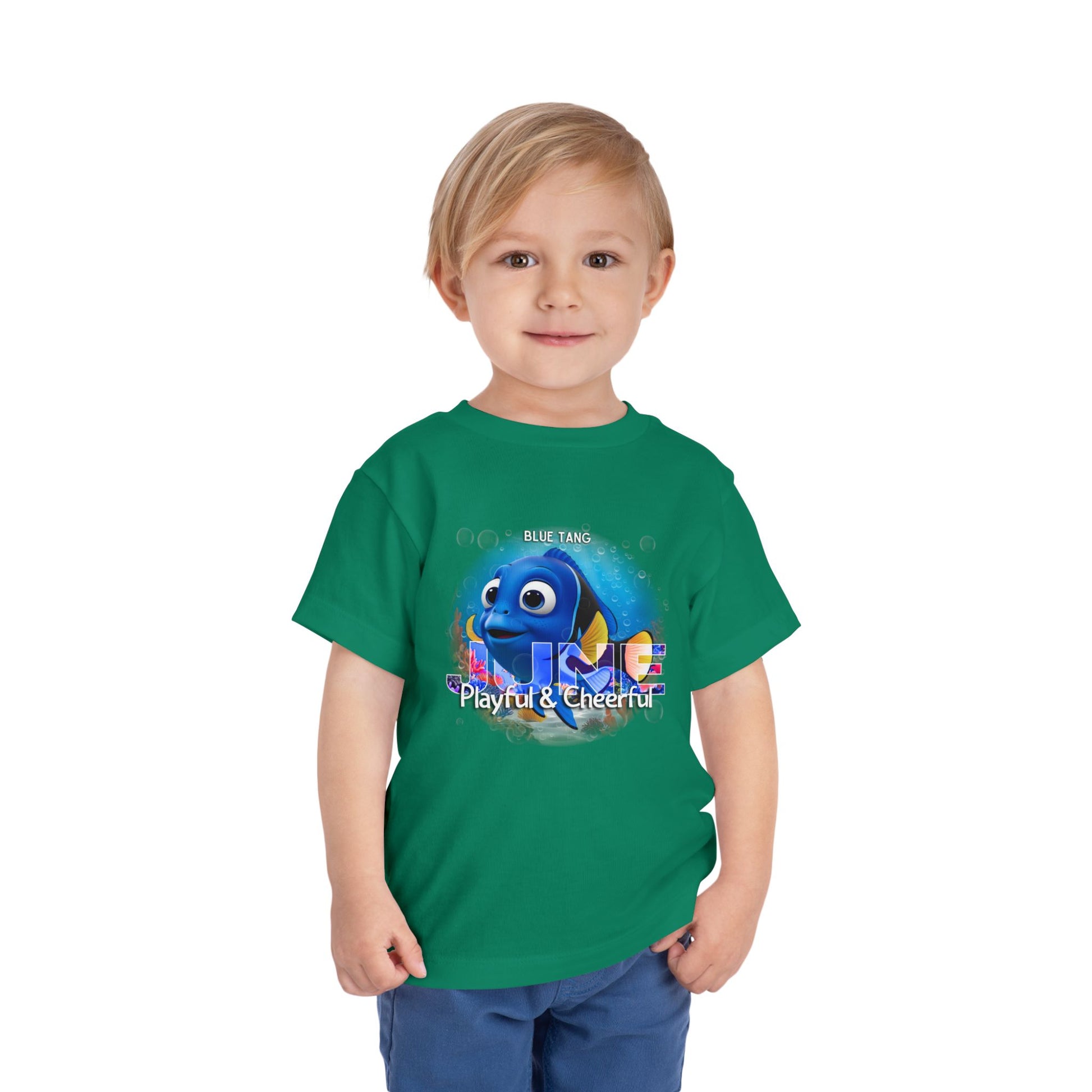 Young boy wearing green kids birth month tshirt with playful blue tang fish design 