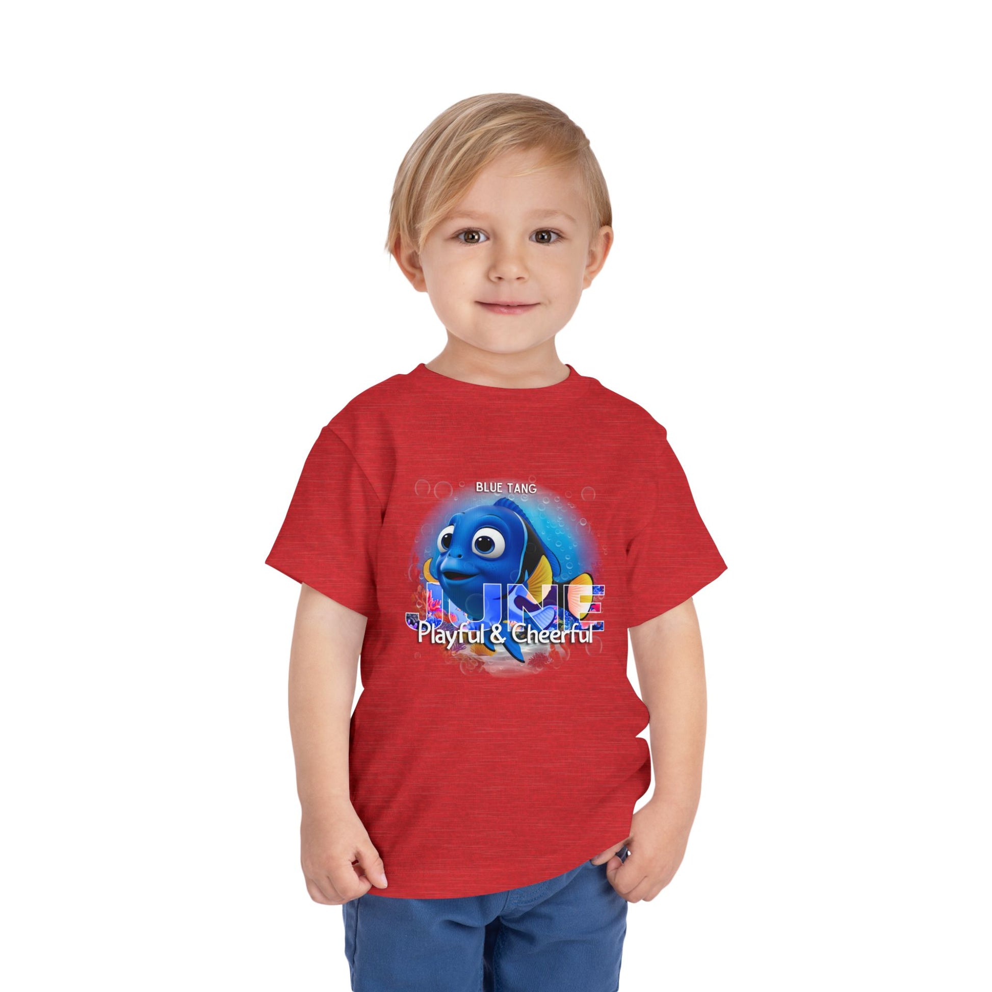 Toddler wearing a red kids birth month tshirt with a playful blue fish graphic 